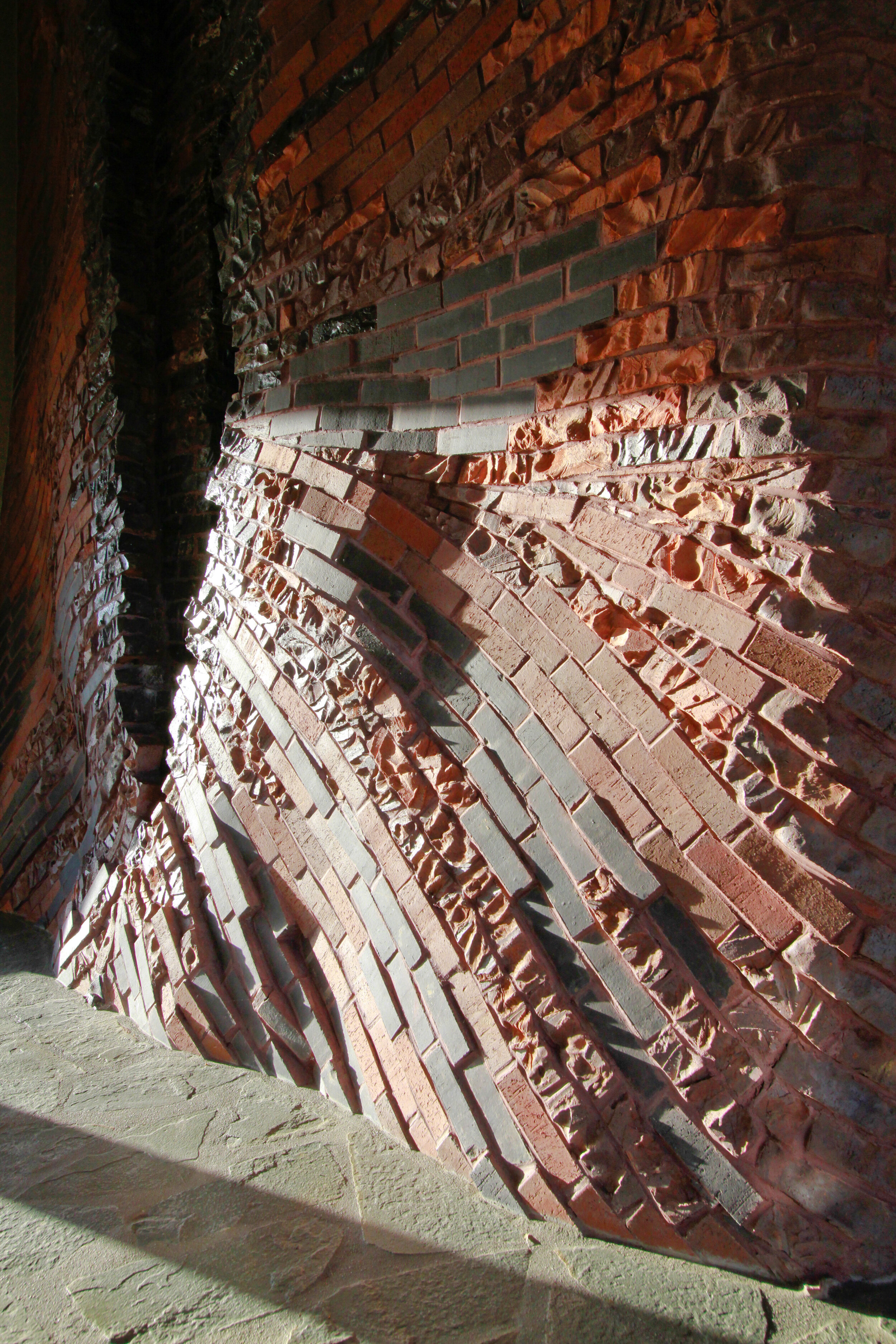 detail of carved brickwork wall fountain showing striated black and red bricks
