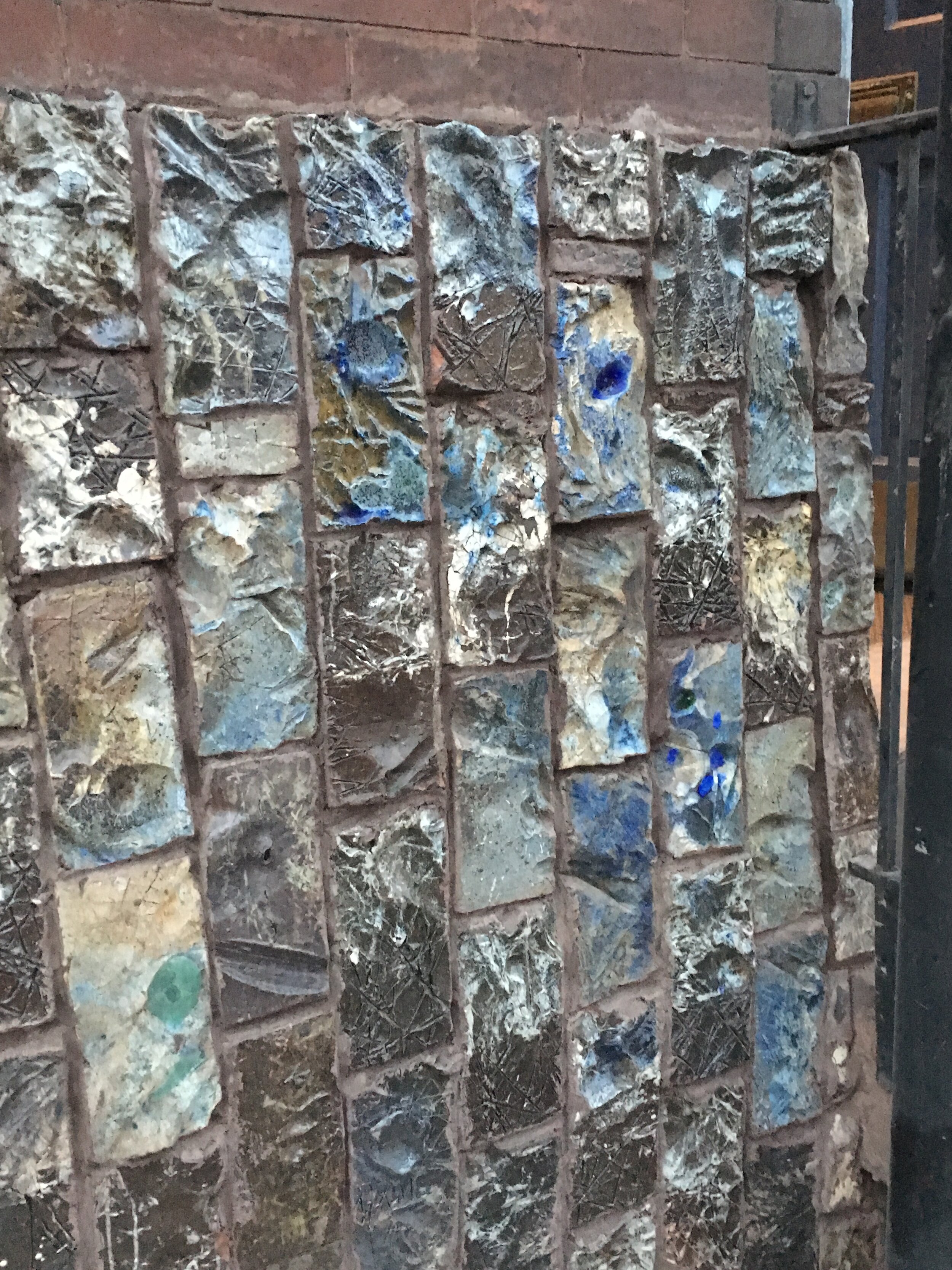 Wall of Artist's house- colorful salt glazed bricks of blues and greens on wall of home