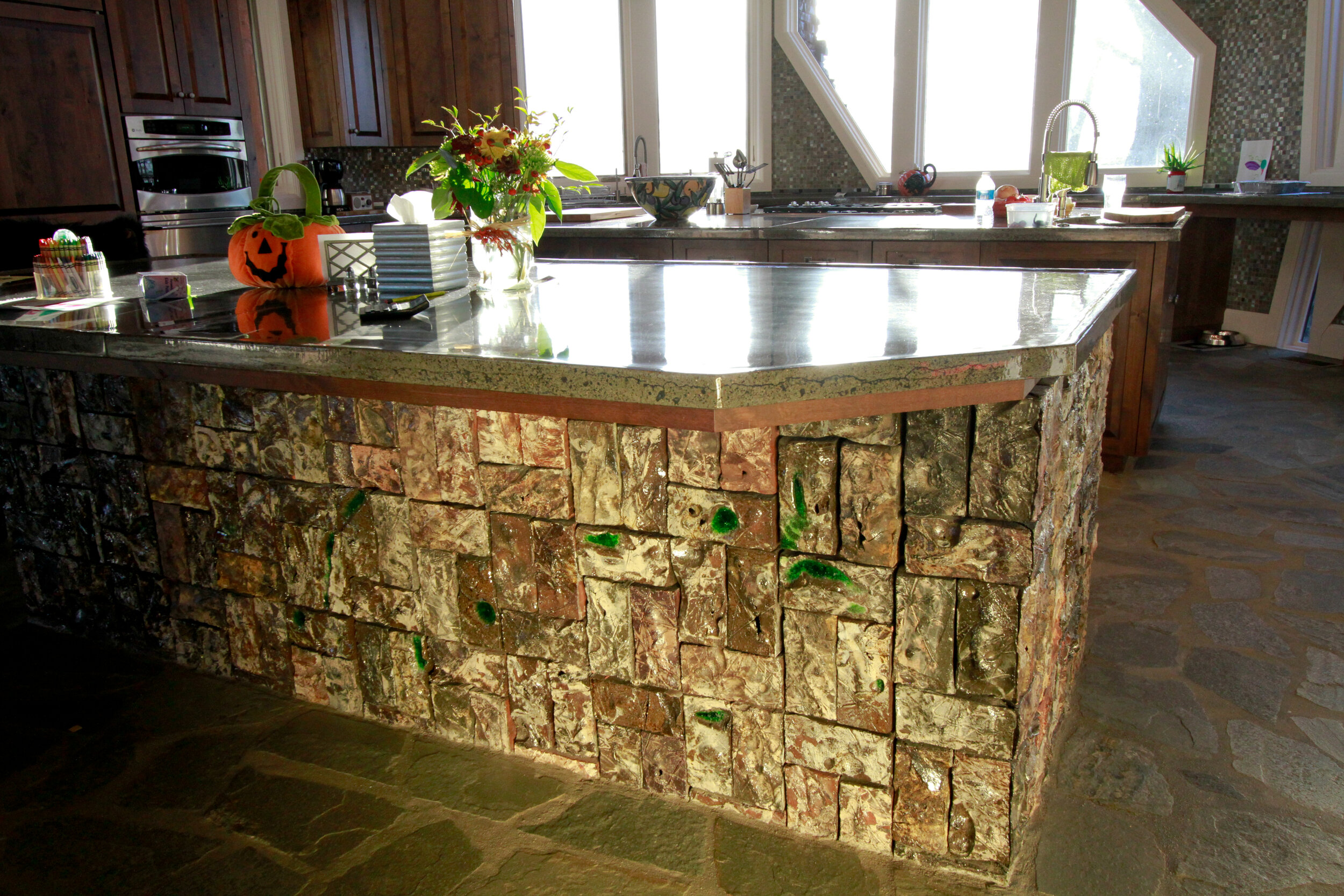 Colorful salt glazed textured brickwork surface makes this . unique kitchen island in modern home.