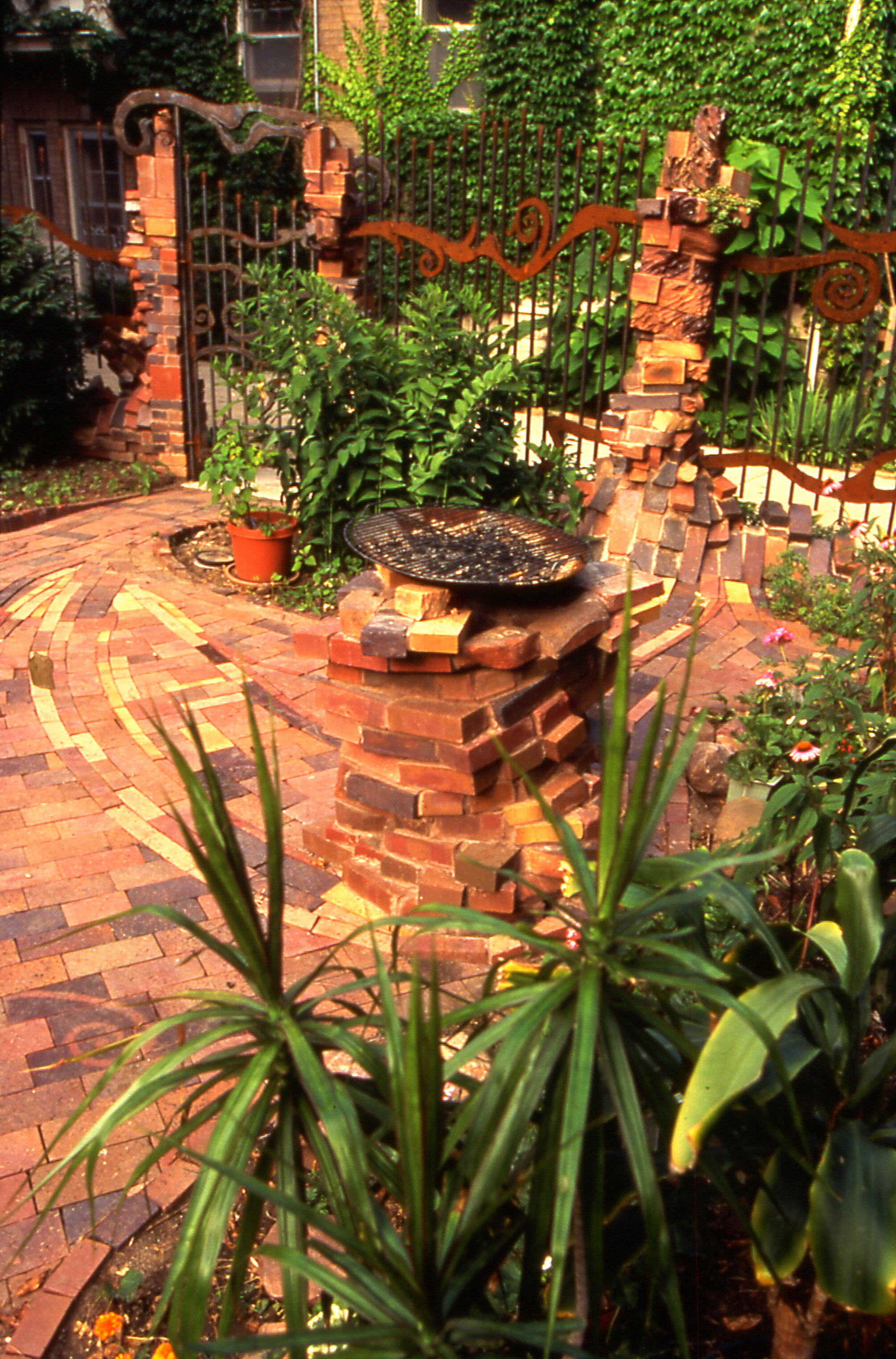 Keraunos patio with central planter on column, all of carved bricks, red, brown, yellow