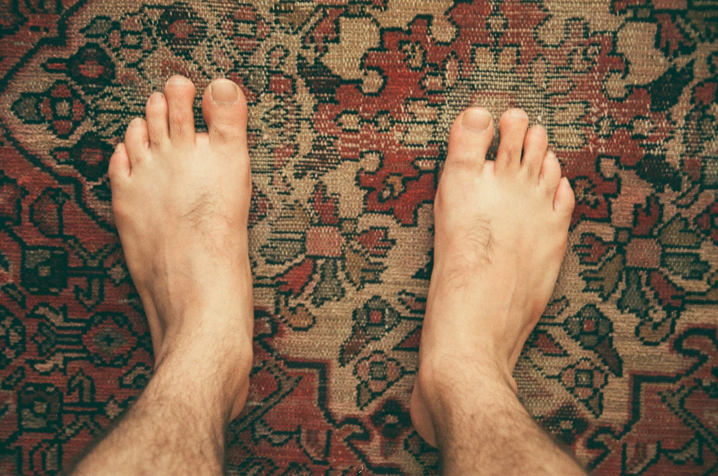 Two bare feet on an old patterned rug