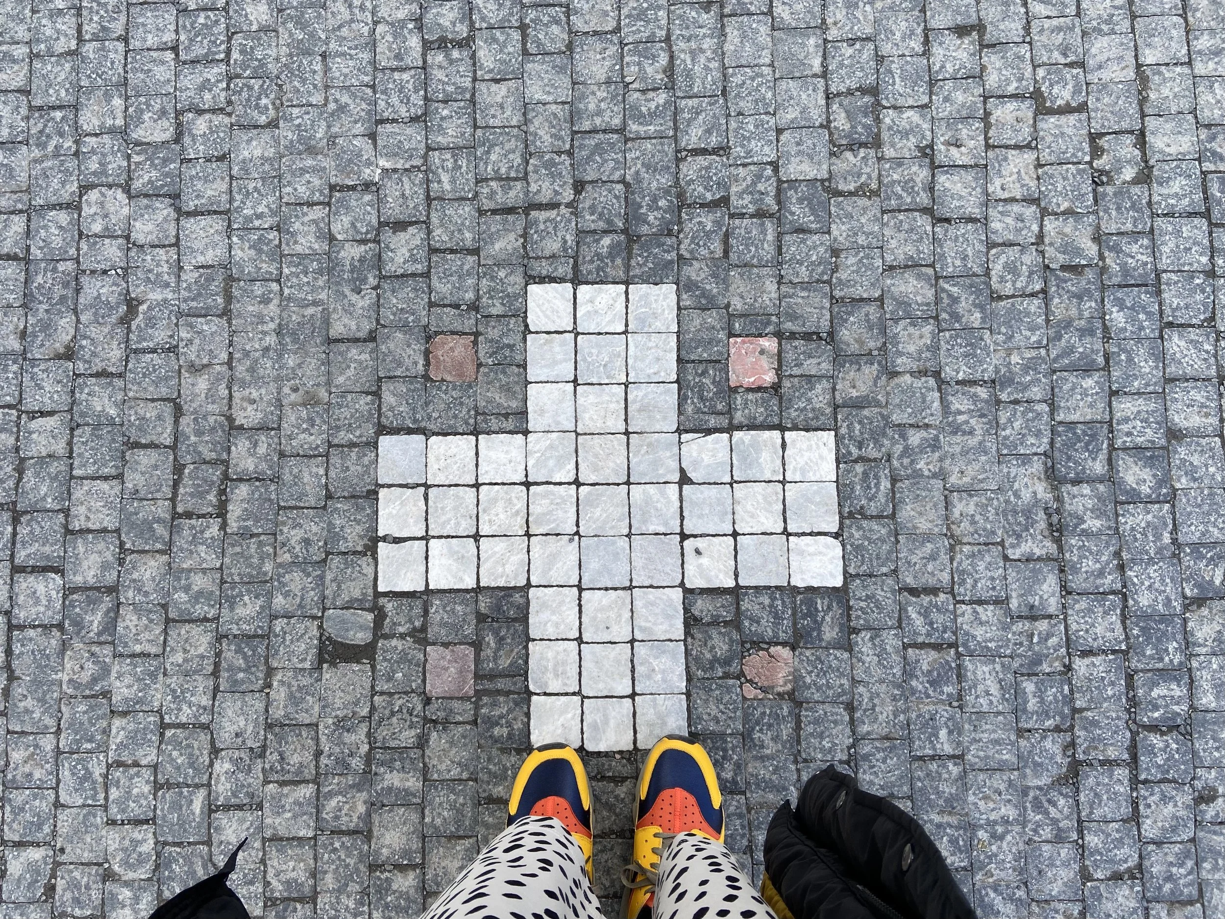 Tanya Paget standing on the ornate cobbled square outside Prague's Astronomical Clock, bright yellow trainers visible against the intricate stone cross pattern - a moment from a recent trip that sparked fresh thinking.