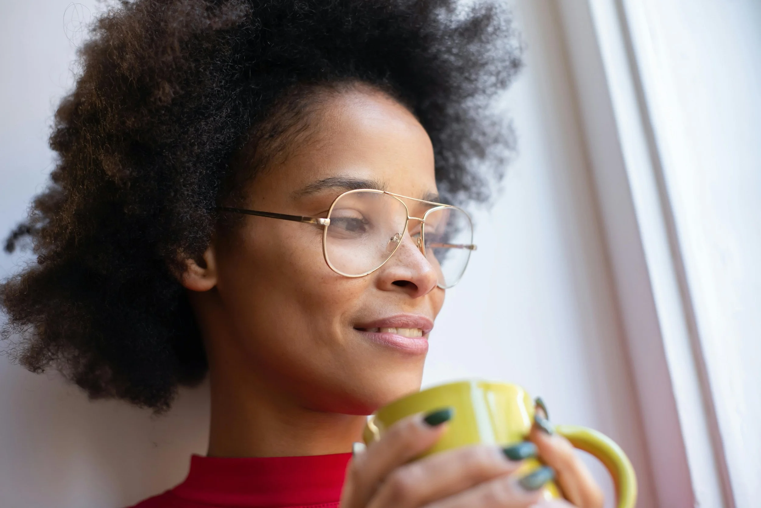 A founder takes a moment to pause and think, holding a coffee cup and looking out of a window.