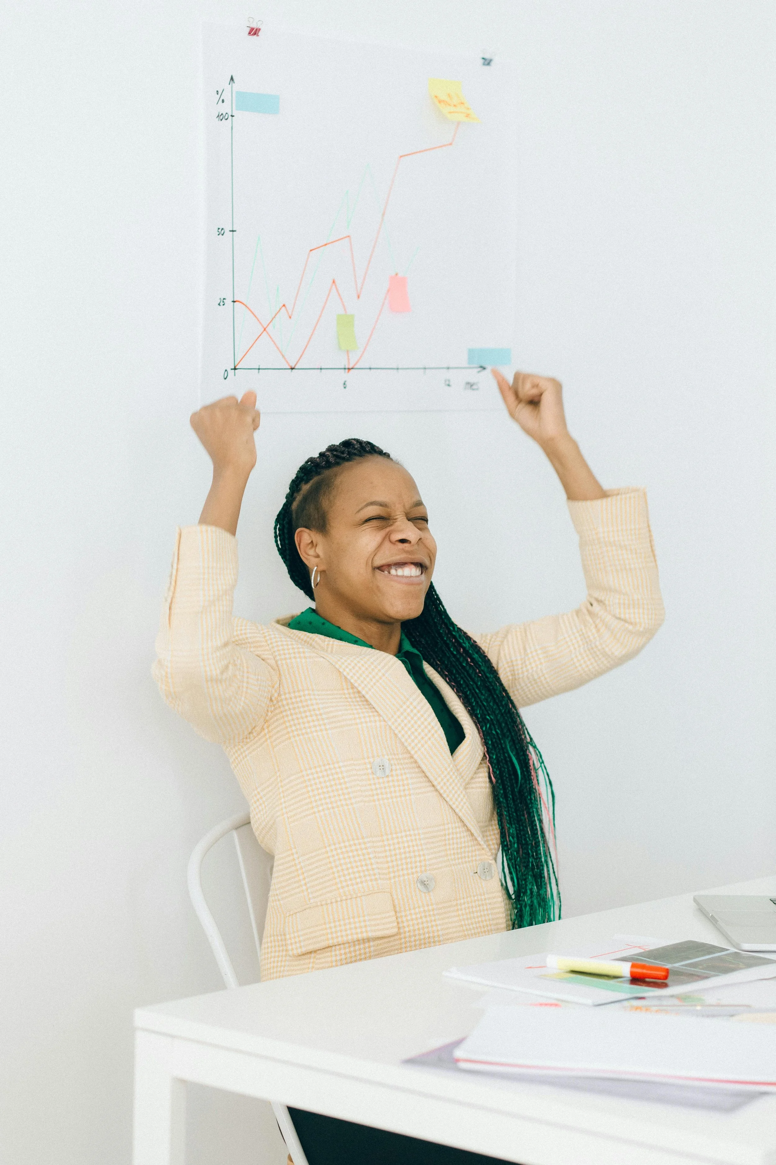 An entreprenur celebrating with her hands in the air at a desk