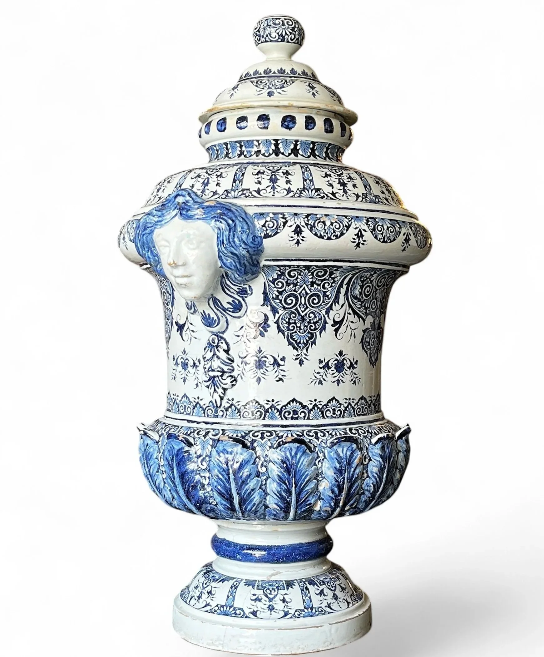 19th-century blue and white glazed earthenware water cistern with domed lid, sculpted female masks, floral motifs and cobalt blue acanthus leaves.