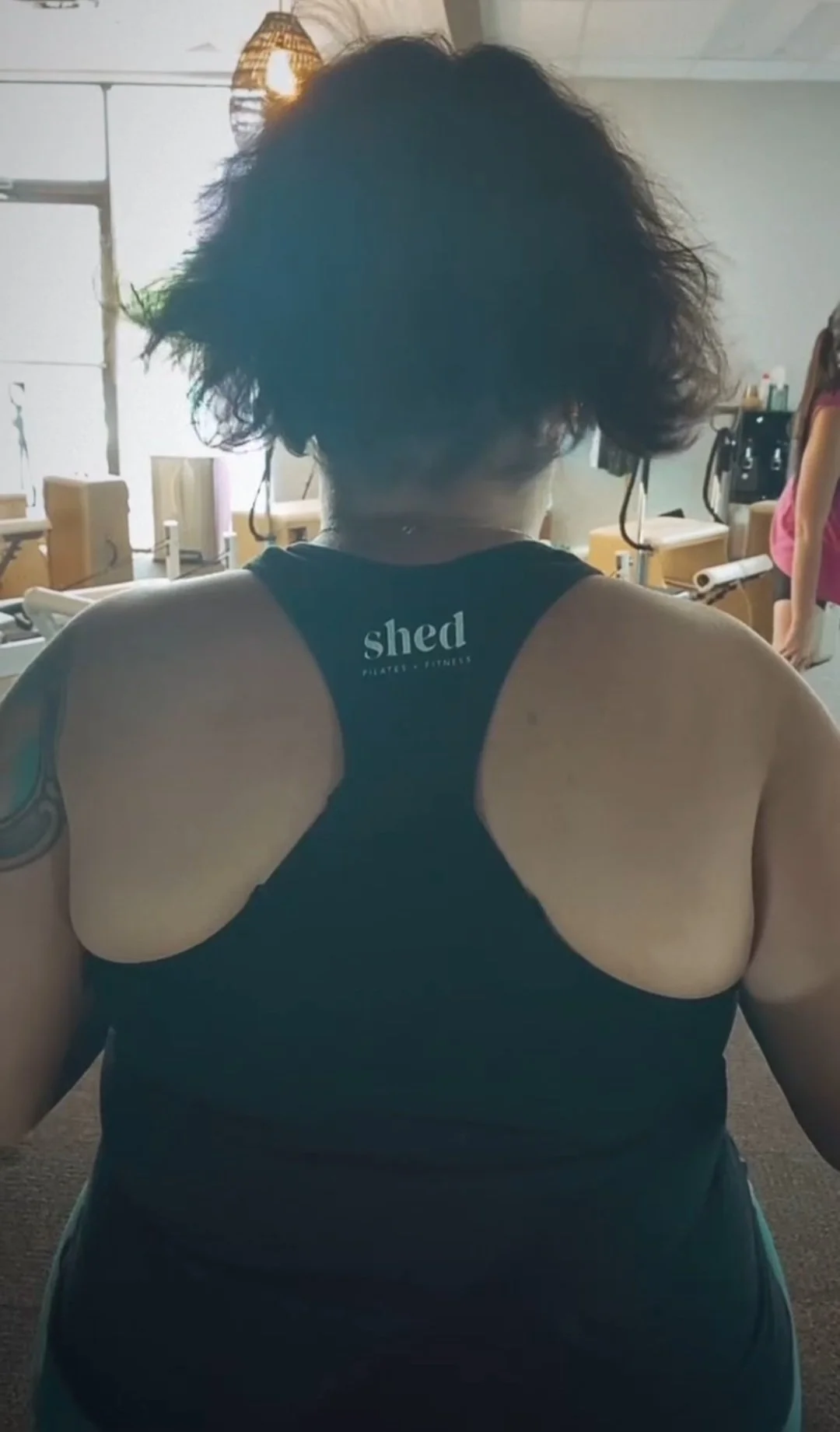 Woman wearing a racerback tank top from Shed Pilates and Fitness.
