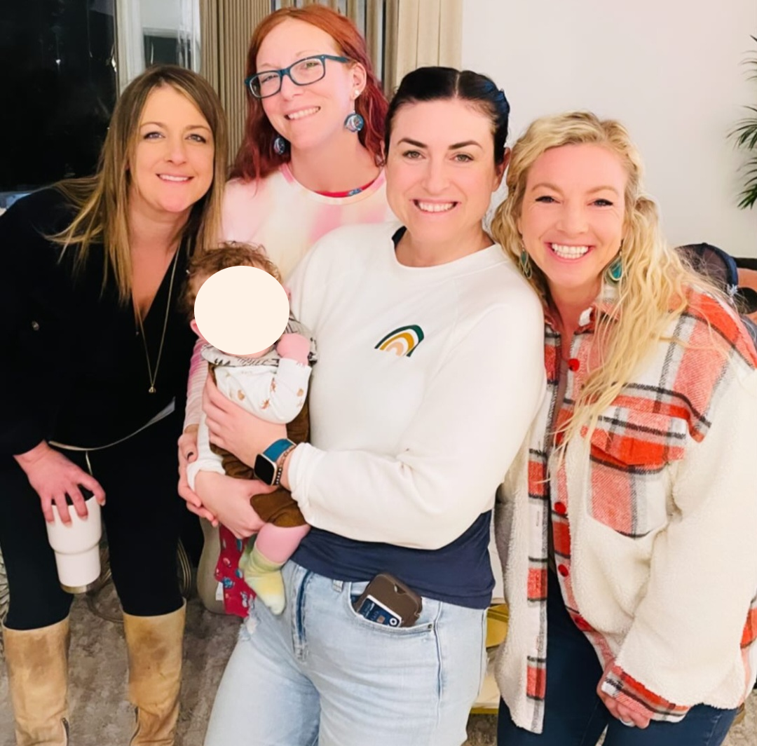 Group of women posing for a picture with a small baby