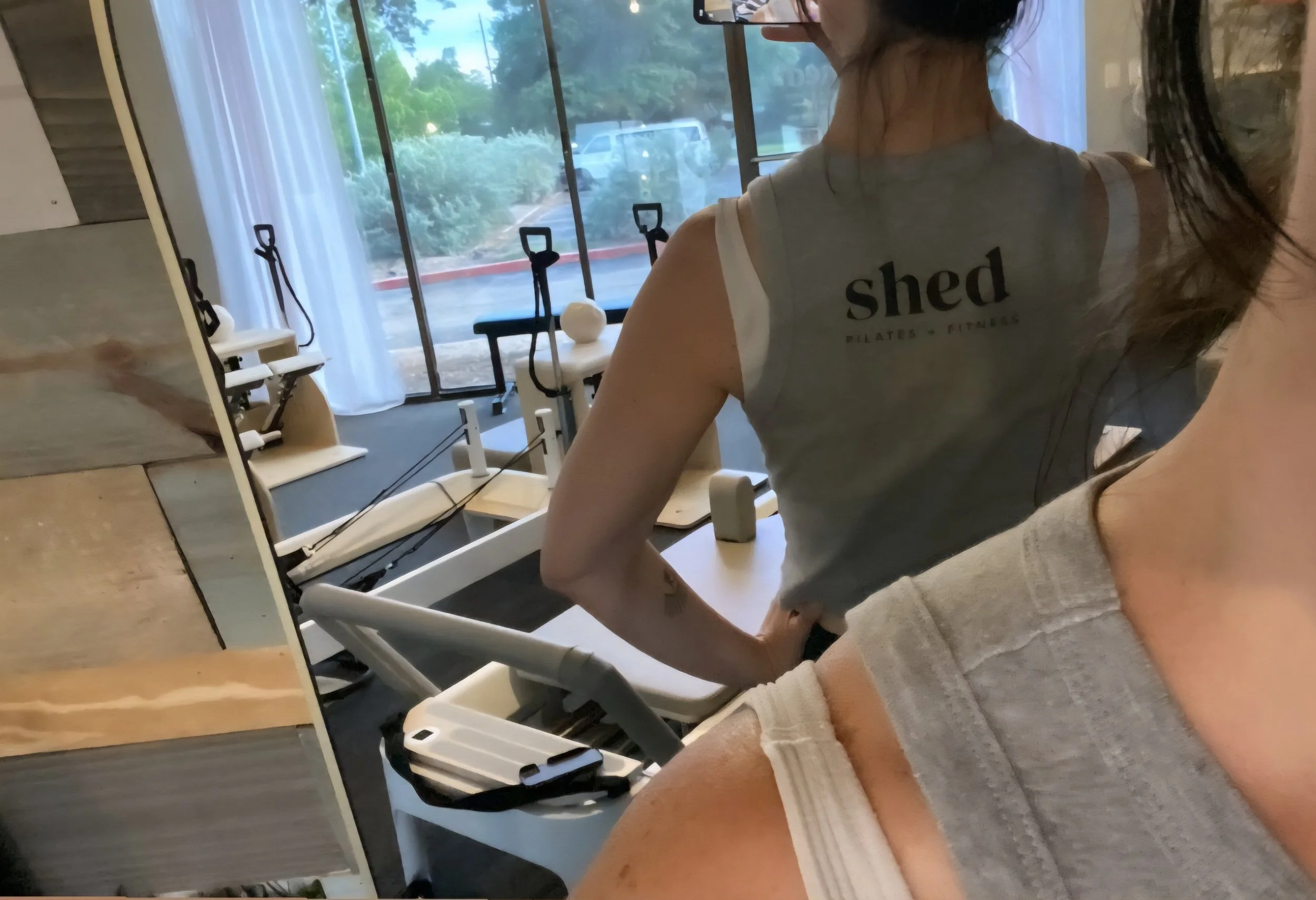 Woman showing the back of a gray ribbed tank top from Shed Pilates and Fitness.