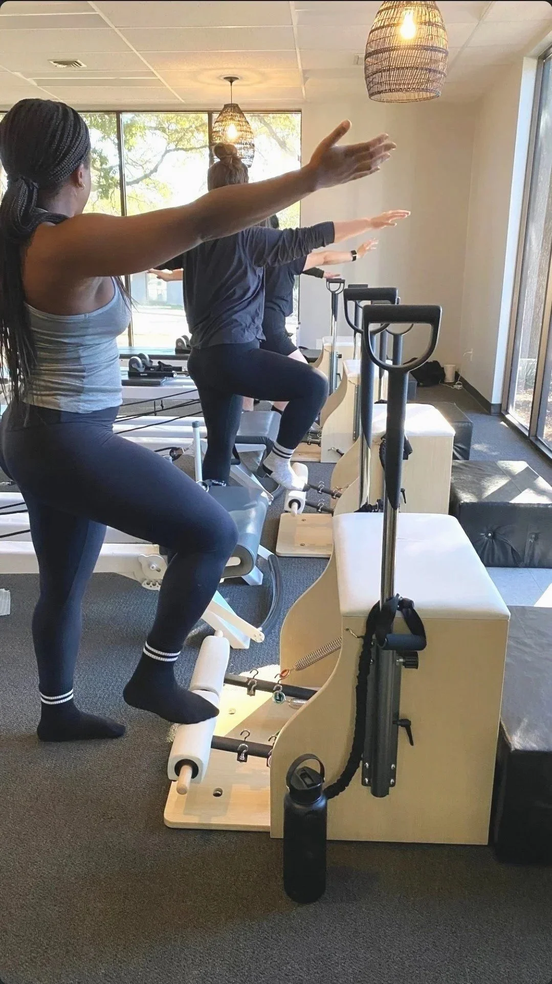 Group of women doing pilates chair exercises on pilates chair in a fitness studio.