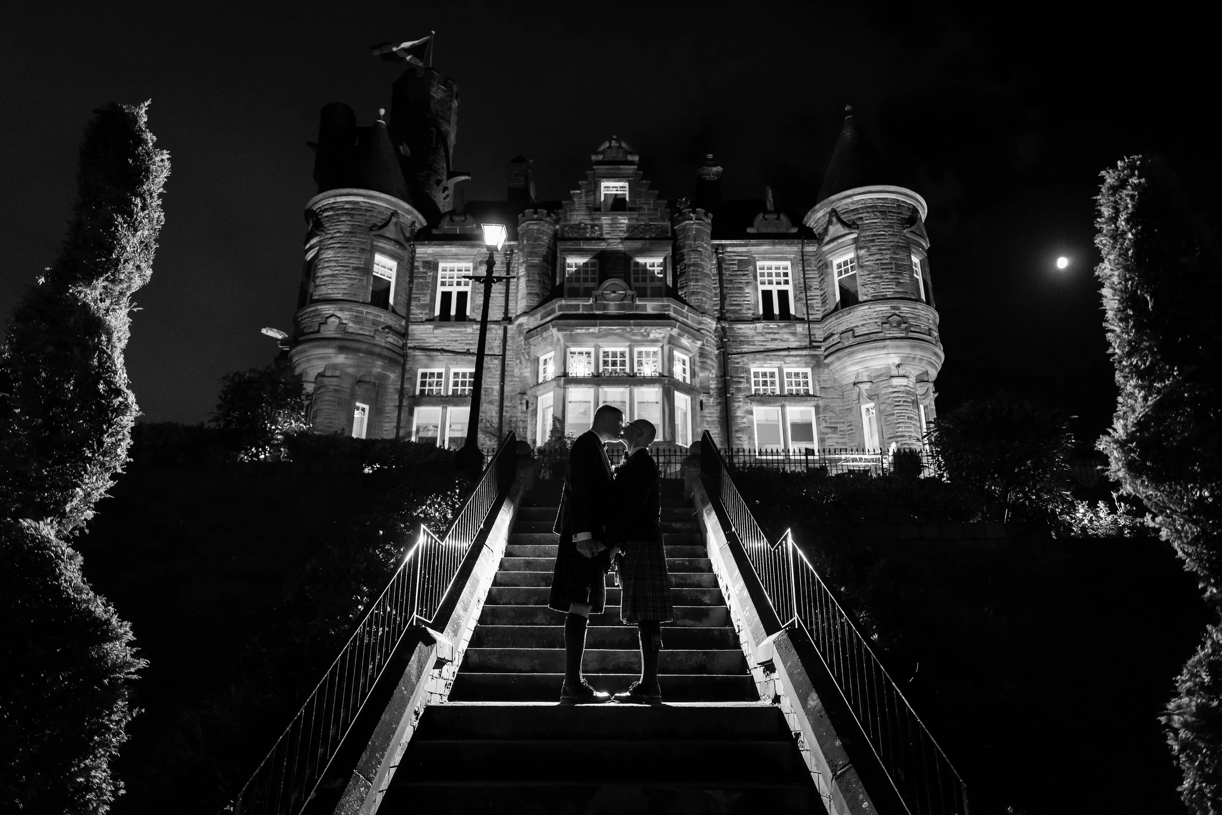 Couple kissing on steps outside Sherbrooke Castle Hotel at night.
