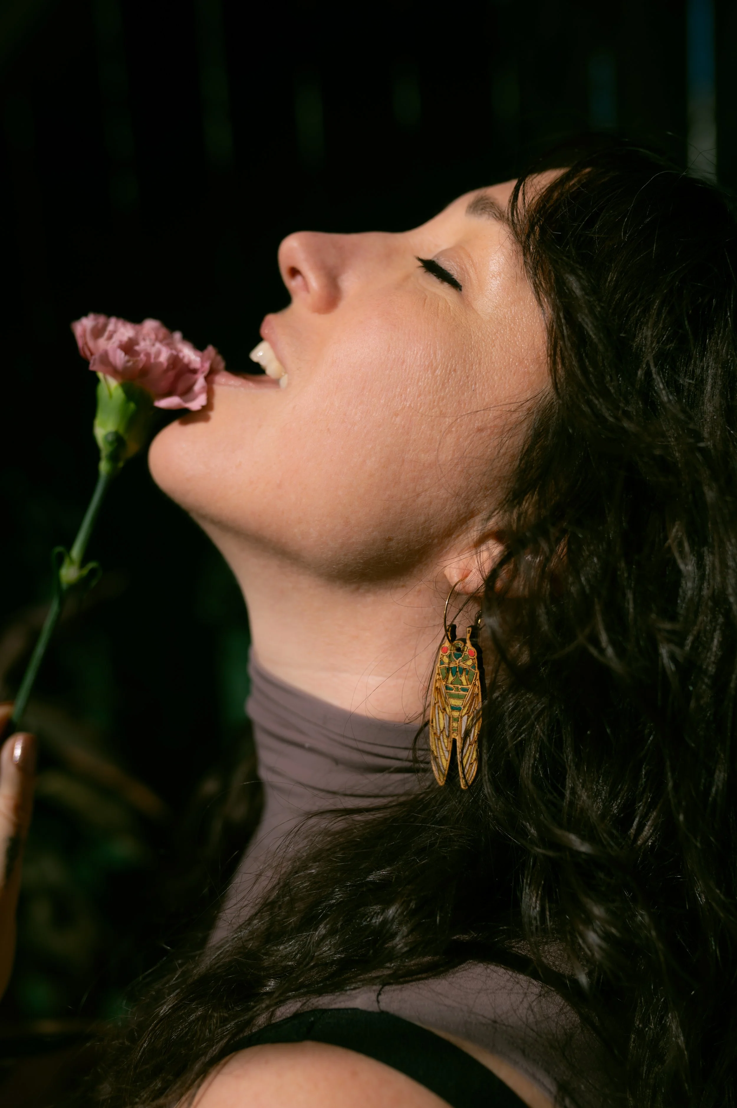 woman leans back in pleasure with a flower to her lips
