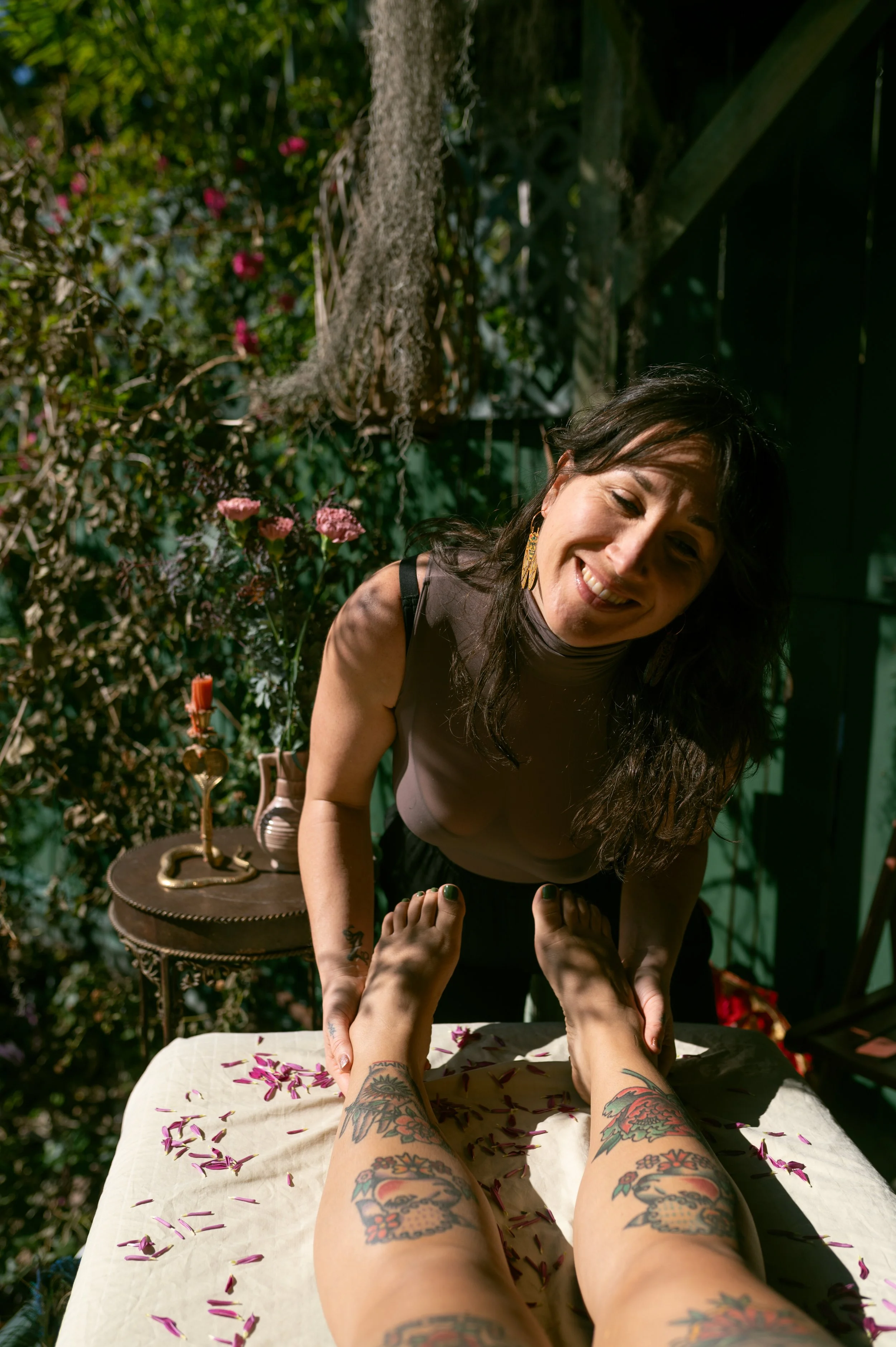 woman smiles lovingly while holding feet surrounded by beautiful nature