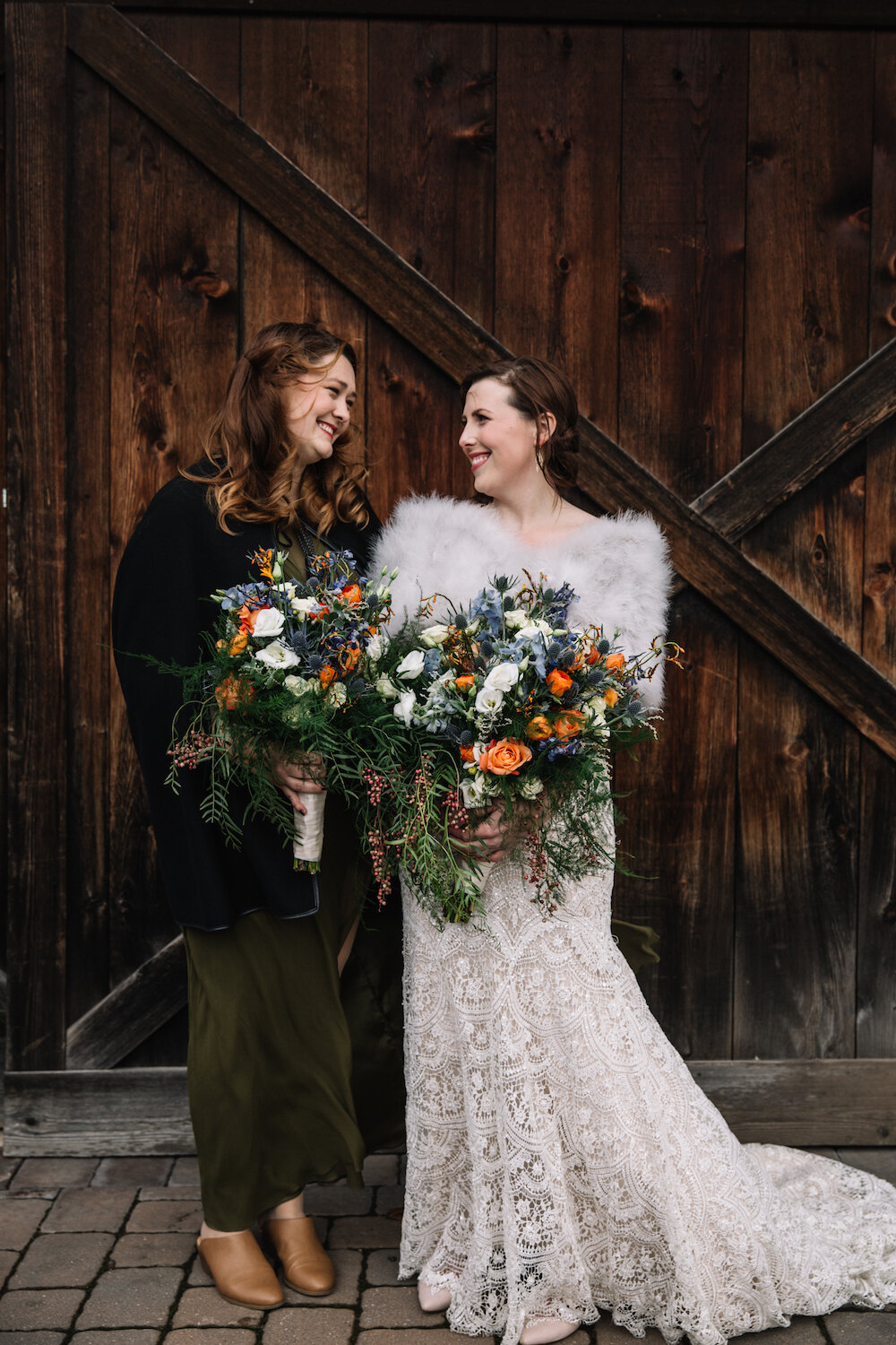 Bride and Maid of Honor standing in front of a rustic barn door at The Inn at Barley Sheaf Farm located in Holicong, PA