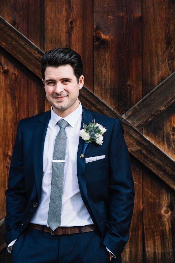 Groom standing in front of a rustic barn door at The Inn at Barley Sheaf Farm located in Holicong, PA