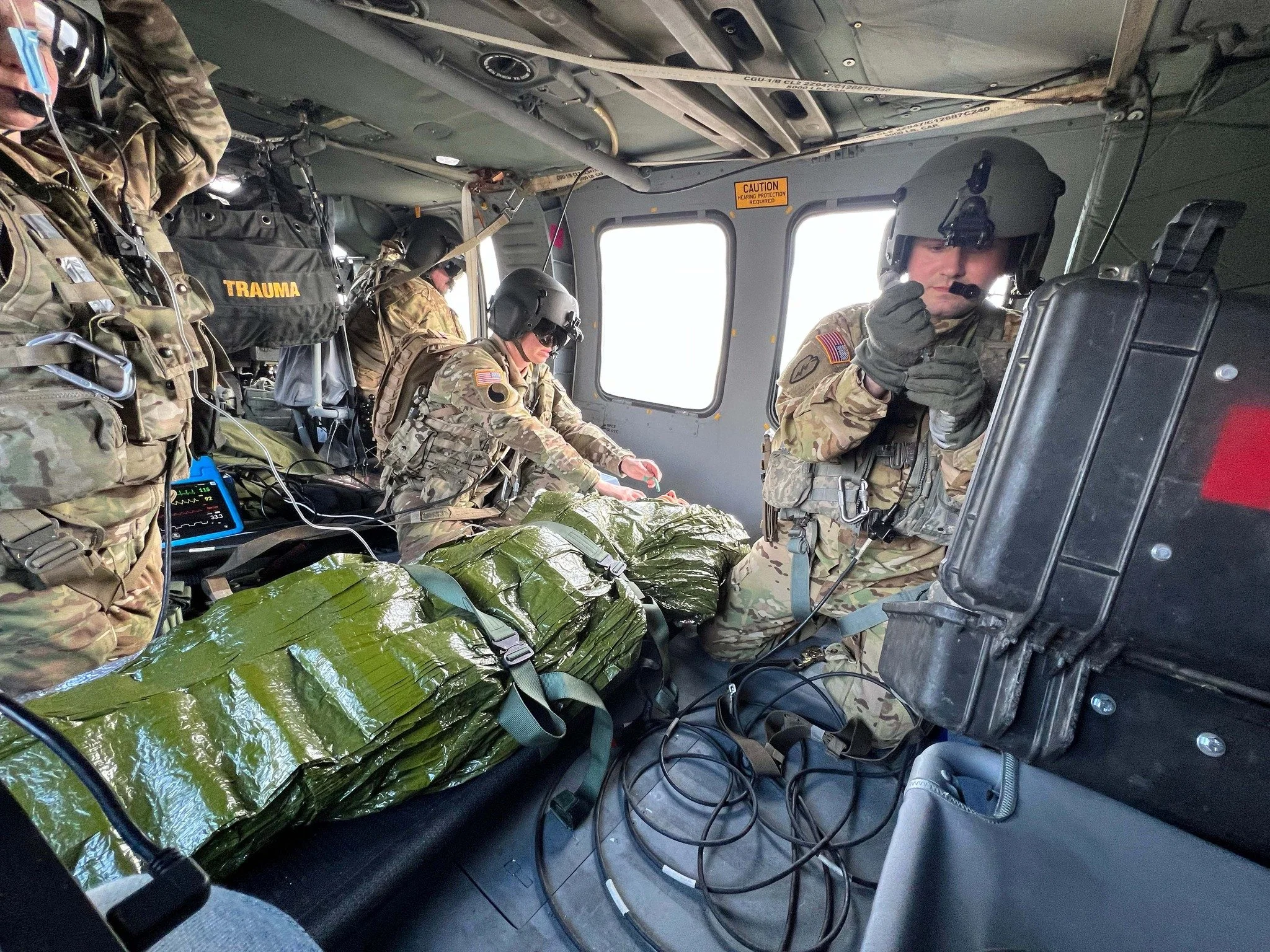 Military medics inside a helicopter preparing medical supplies and equipment for a mission.