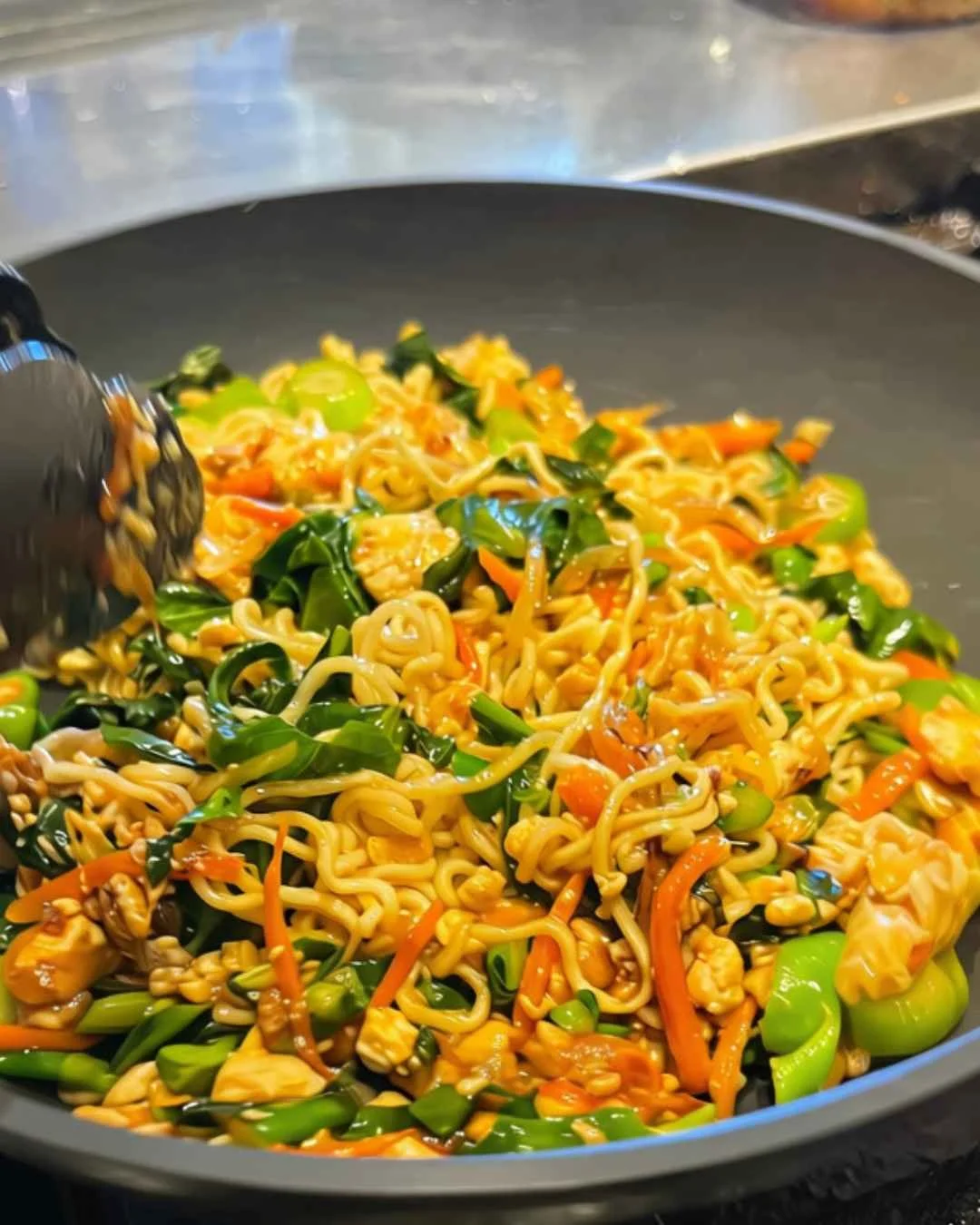 Pad See Ew instant noodles with fried tofu, next to a package of Indomie Mi Goreng