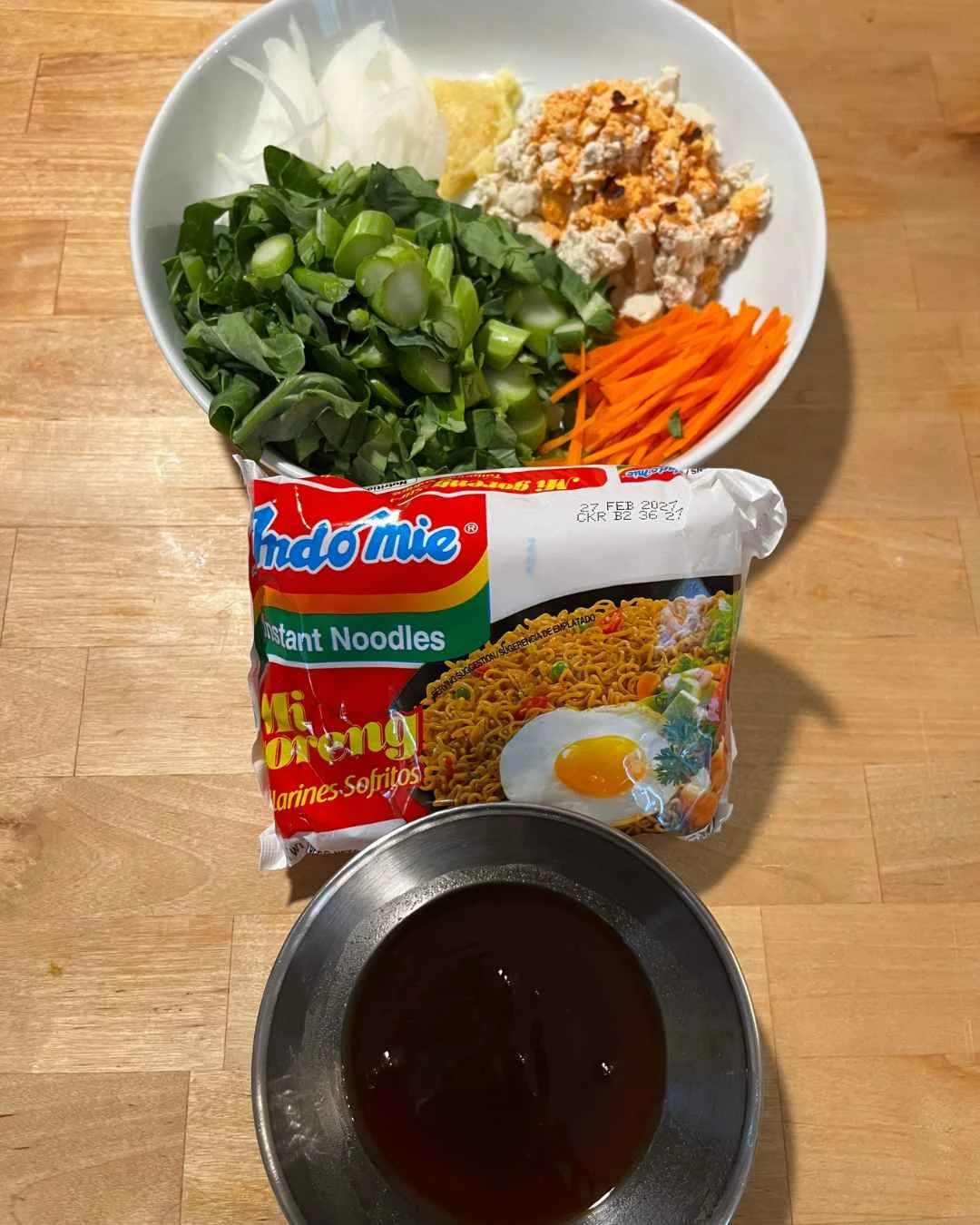 Pad See Ew instant noodles with fried tofu, next to a package of Indomie Mi Goren