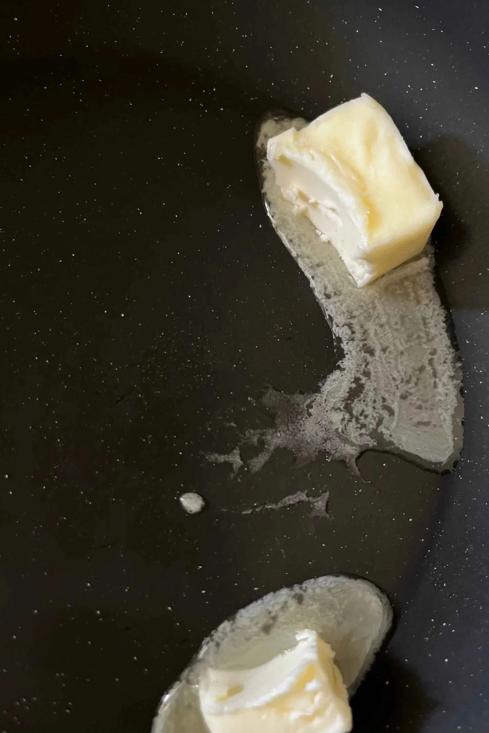 Butter melting and foaming in a black nonstick pan for honey butter tteok