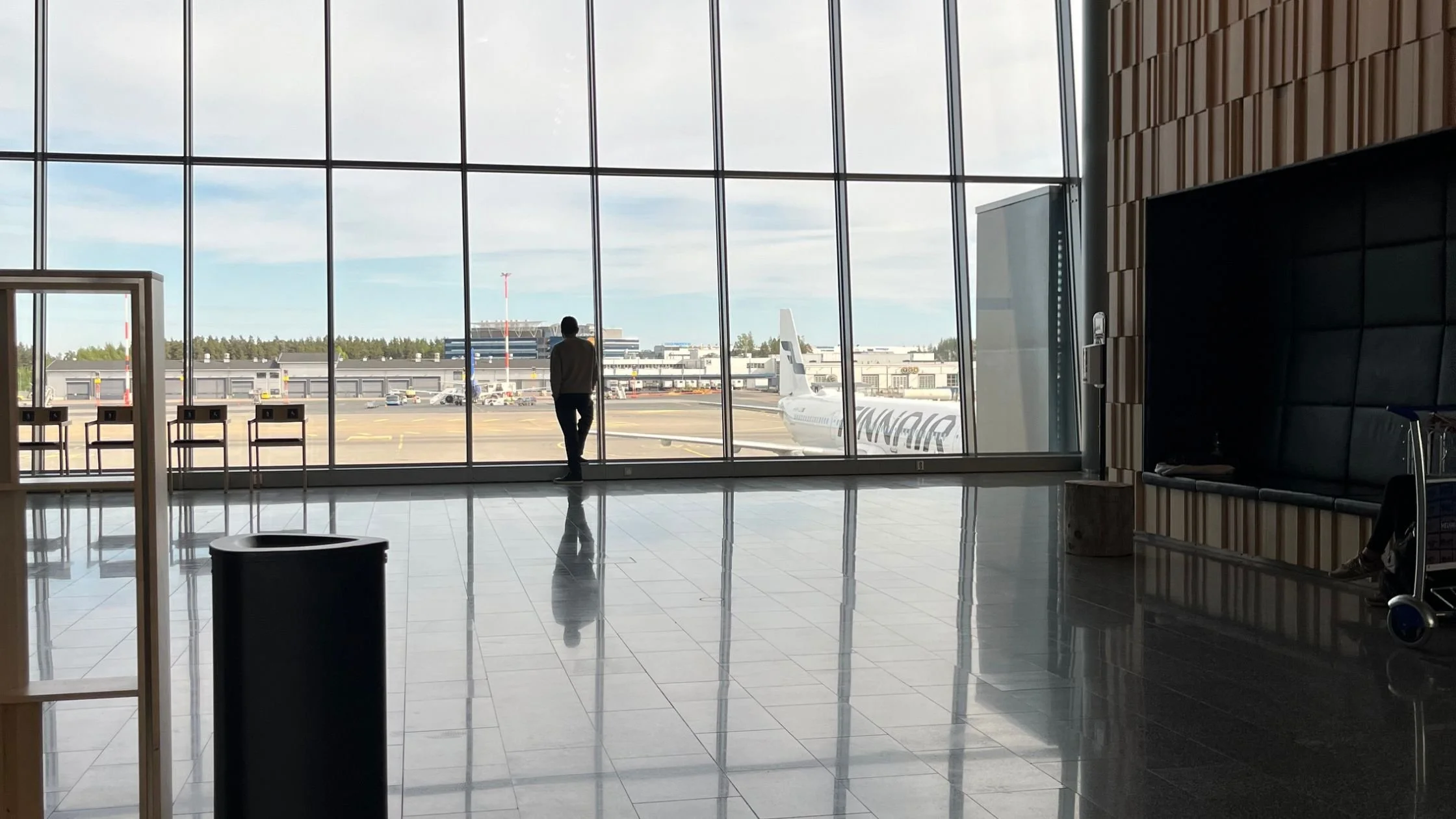 Airport terminal with a traveler looking out at a plane on the tarmac through floor-to-ceiling windows
