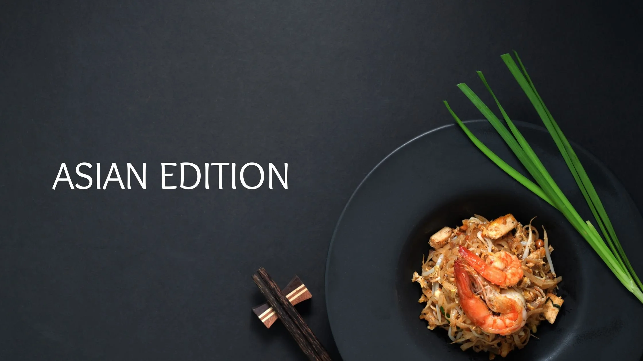 Overhead view of pad thai with shrimp, bean sprouts, and rice noodles on a dark plate with wooden chopsticks and fresh chives on a dark background
