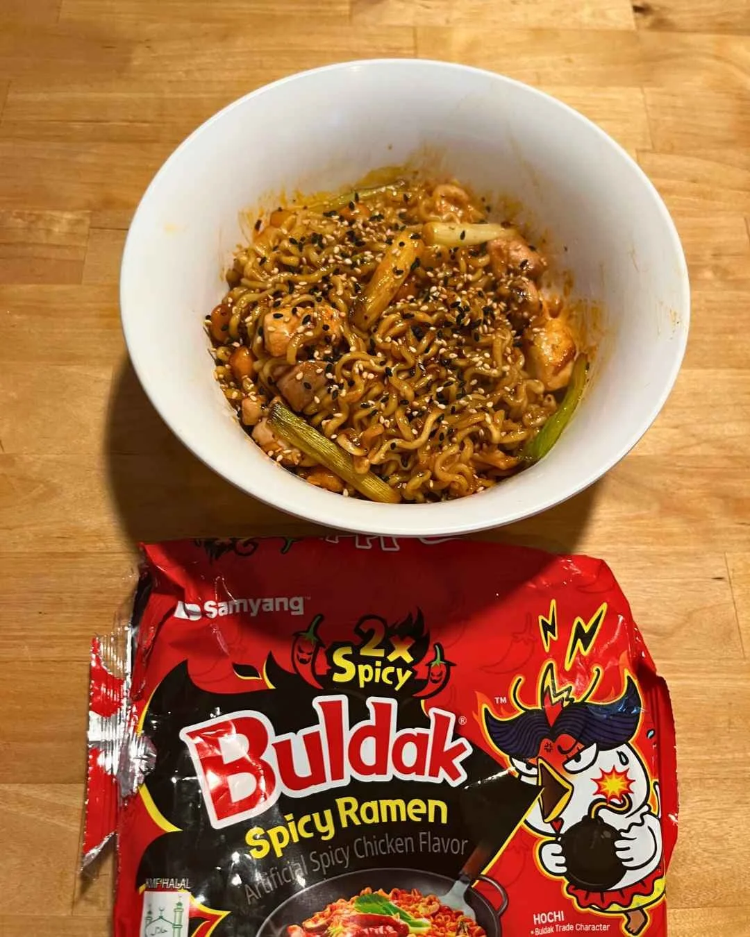 Kung Pao instant noodles with chicken and sesame seeds, next to a package of Buldak Spicy Ramen