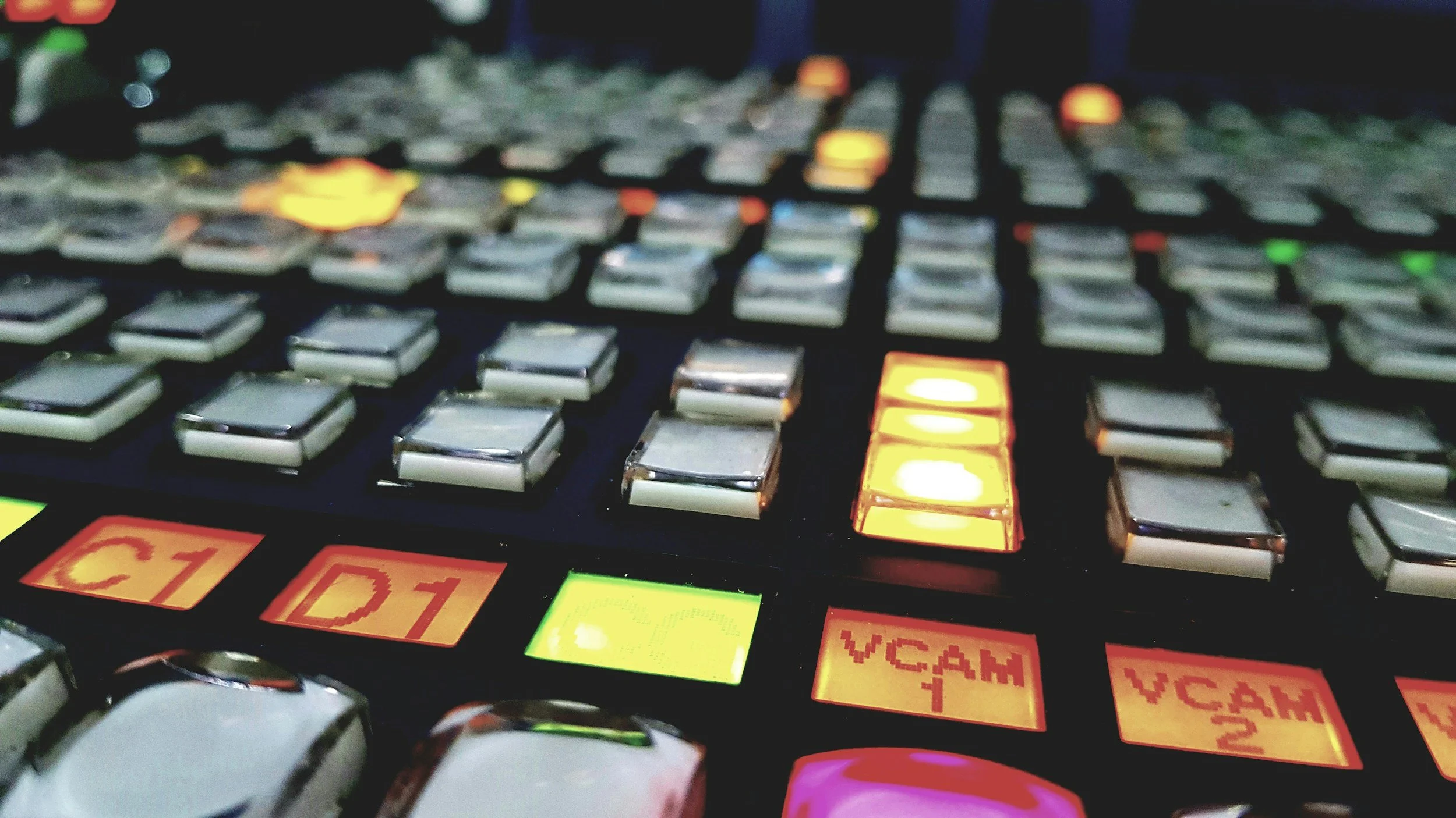Close-up of a professional video switcher with illuminated input and transition controls.
