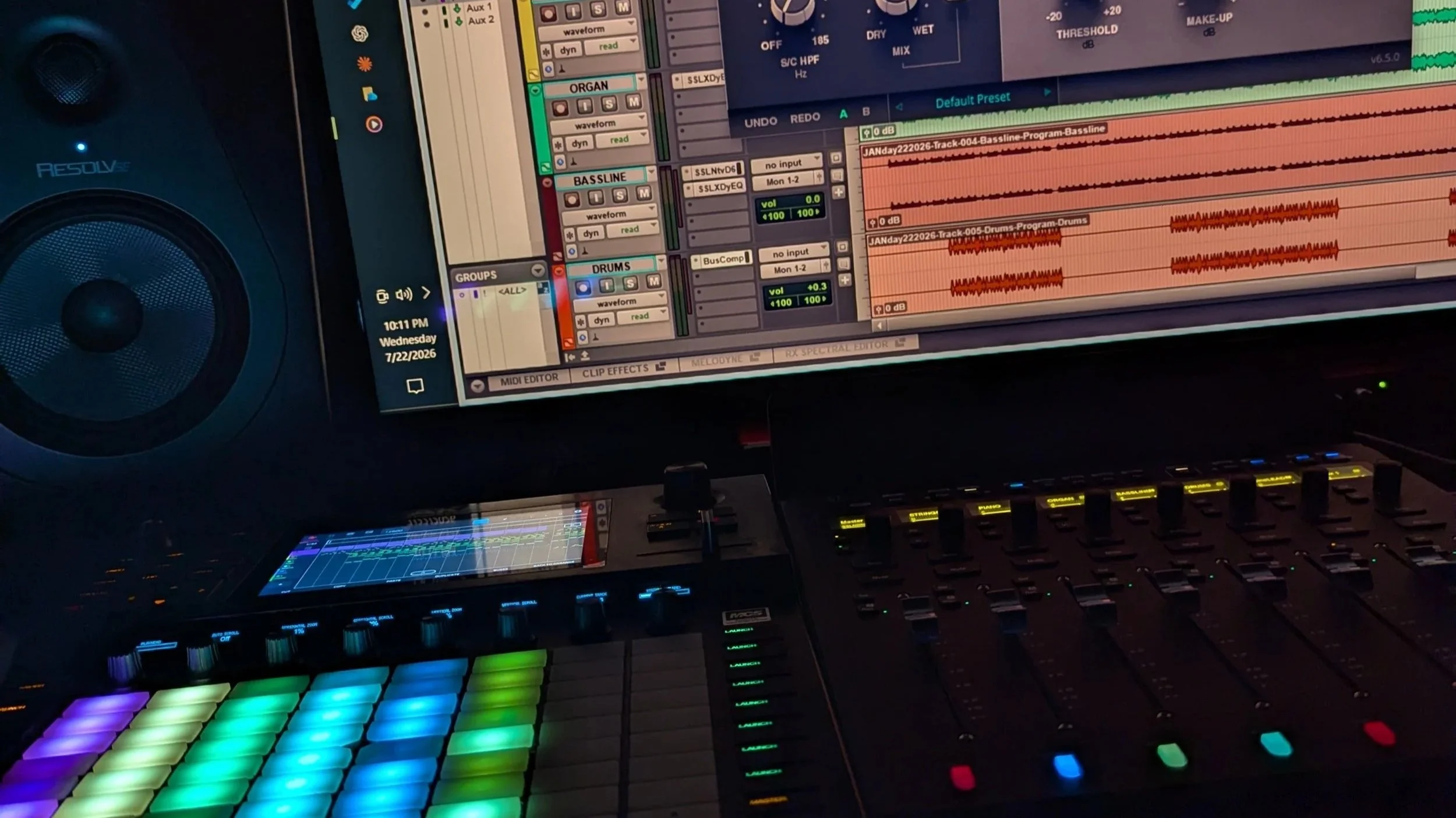 Music production workstation with studio monitors, a DAW session, MIDI controller, and illuminated production controls.