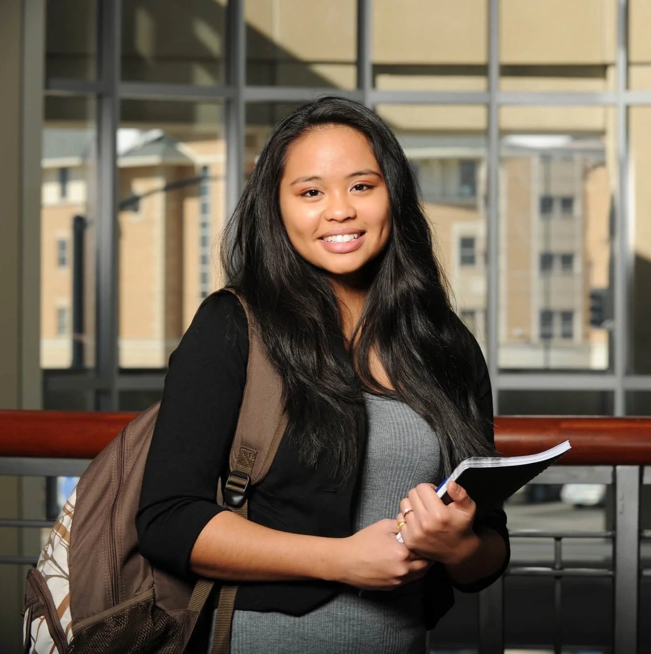 Asian female college student with a backpack and notebook for college student counseling in Atlanta.