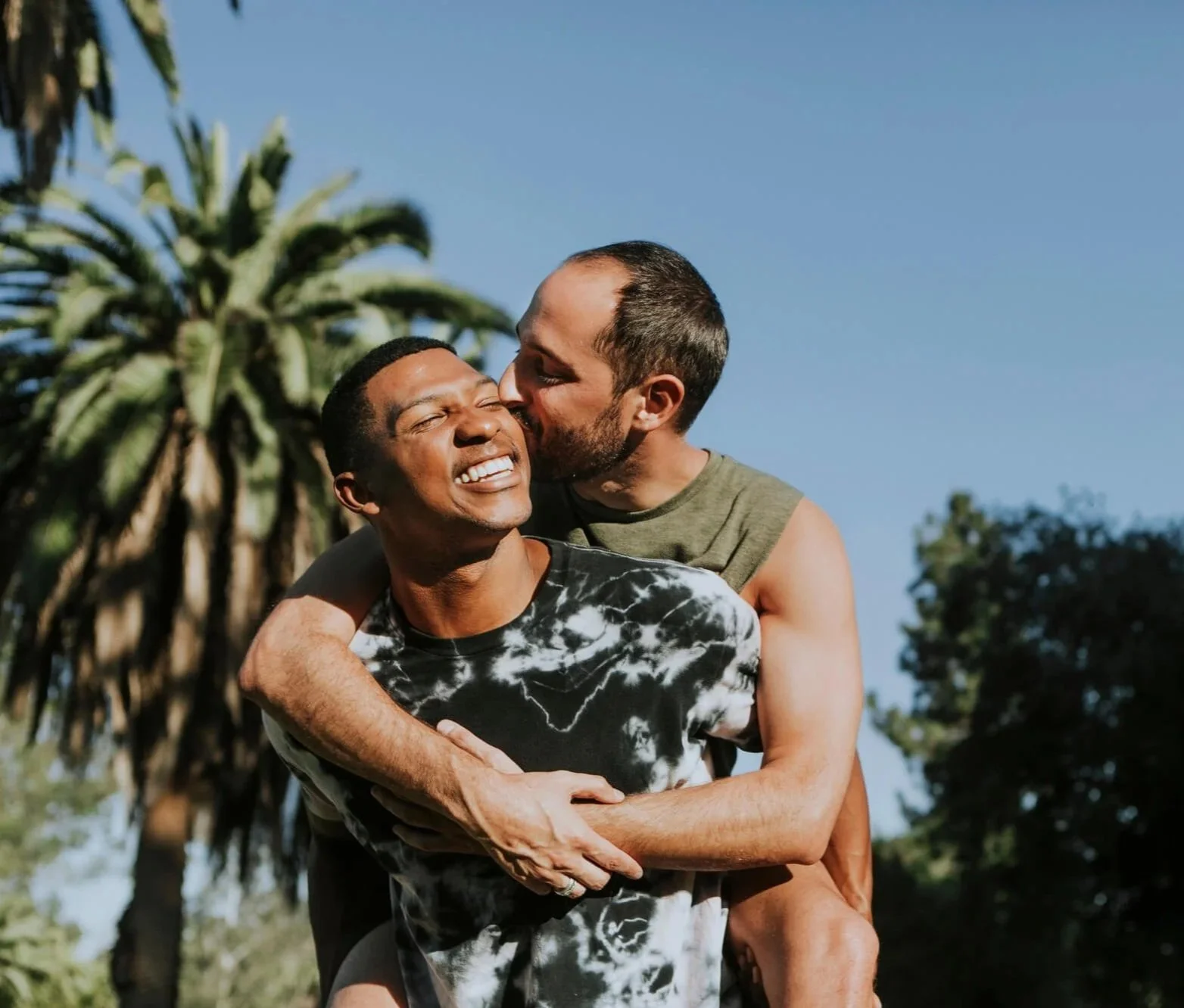 Gay interracial couple embracing outdoors, representing connection and support through LGBTQ+ affirming therapy in Atlanta.