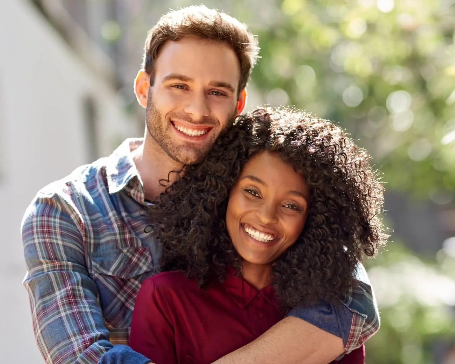 Smiling interracial couple embracing outdoors, representing marriage counseling in Atlanta and Dunwoody, GA.