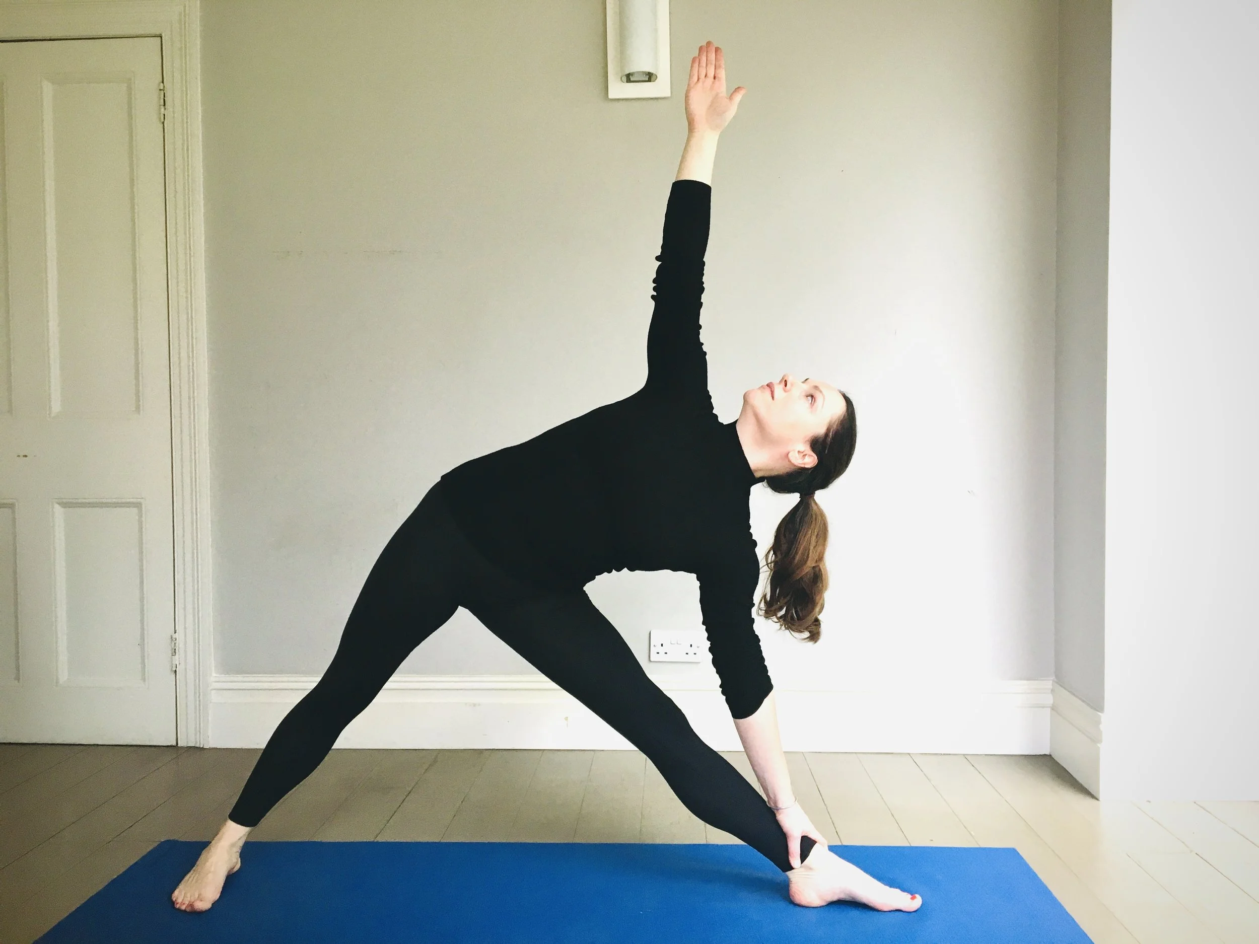 Image of yoga teacher doing triangle pose or Trikonasana Iyengar Yoga drishti standing poses in yoga