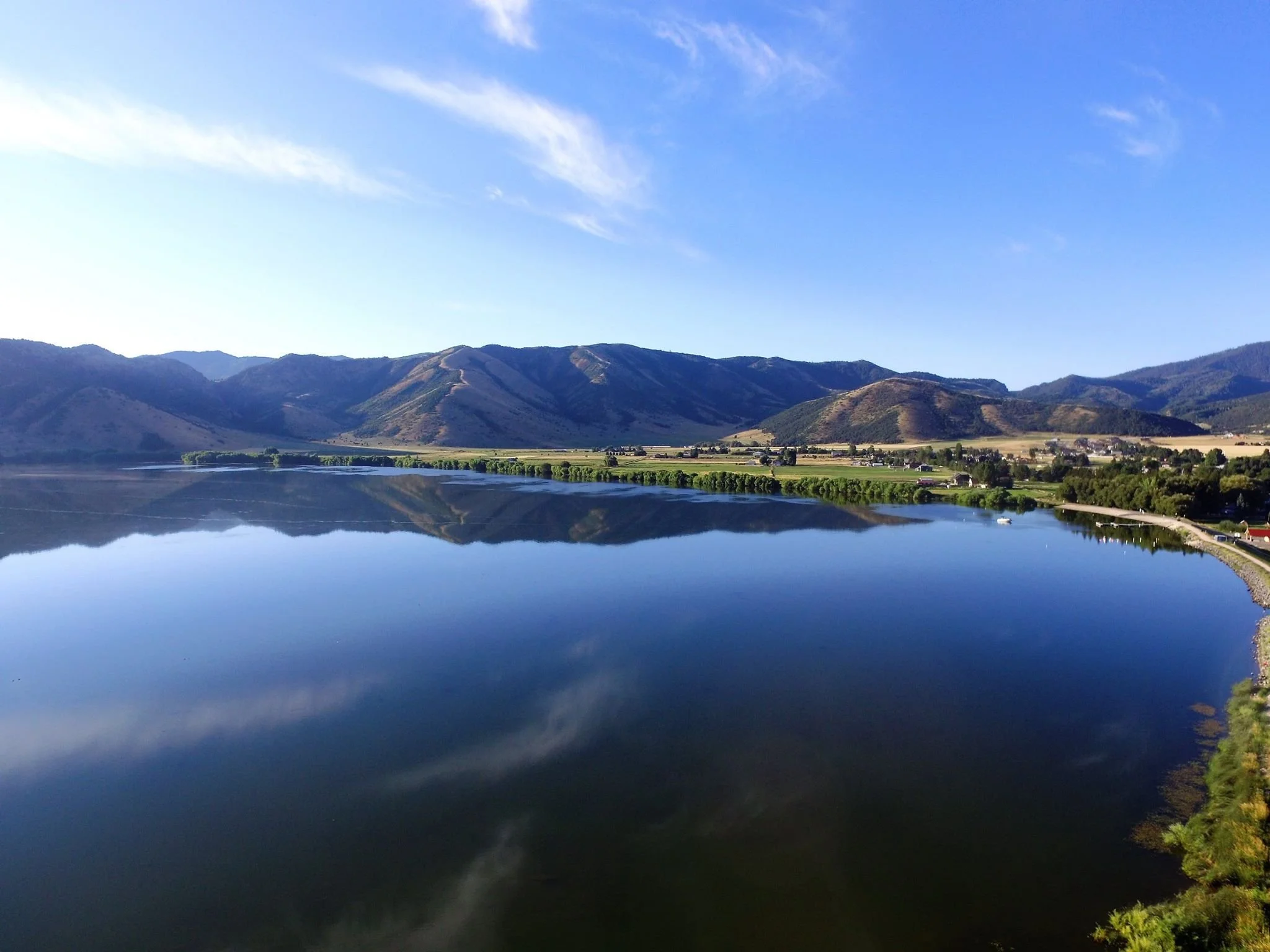 Scenic view of a calm lake reflecting surrounding mountains and a clear blue sky.
