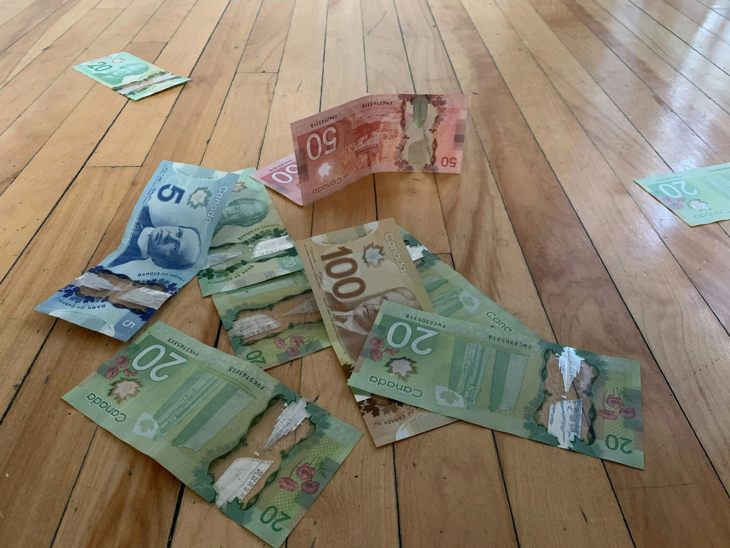 Canadian money bills on a wooden floor.