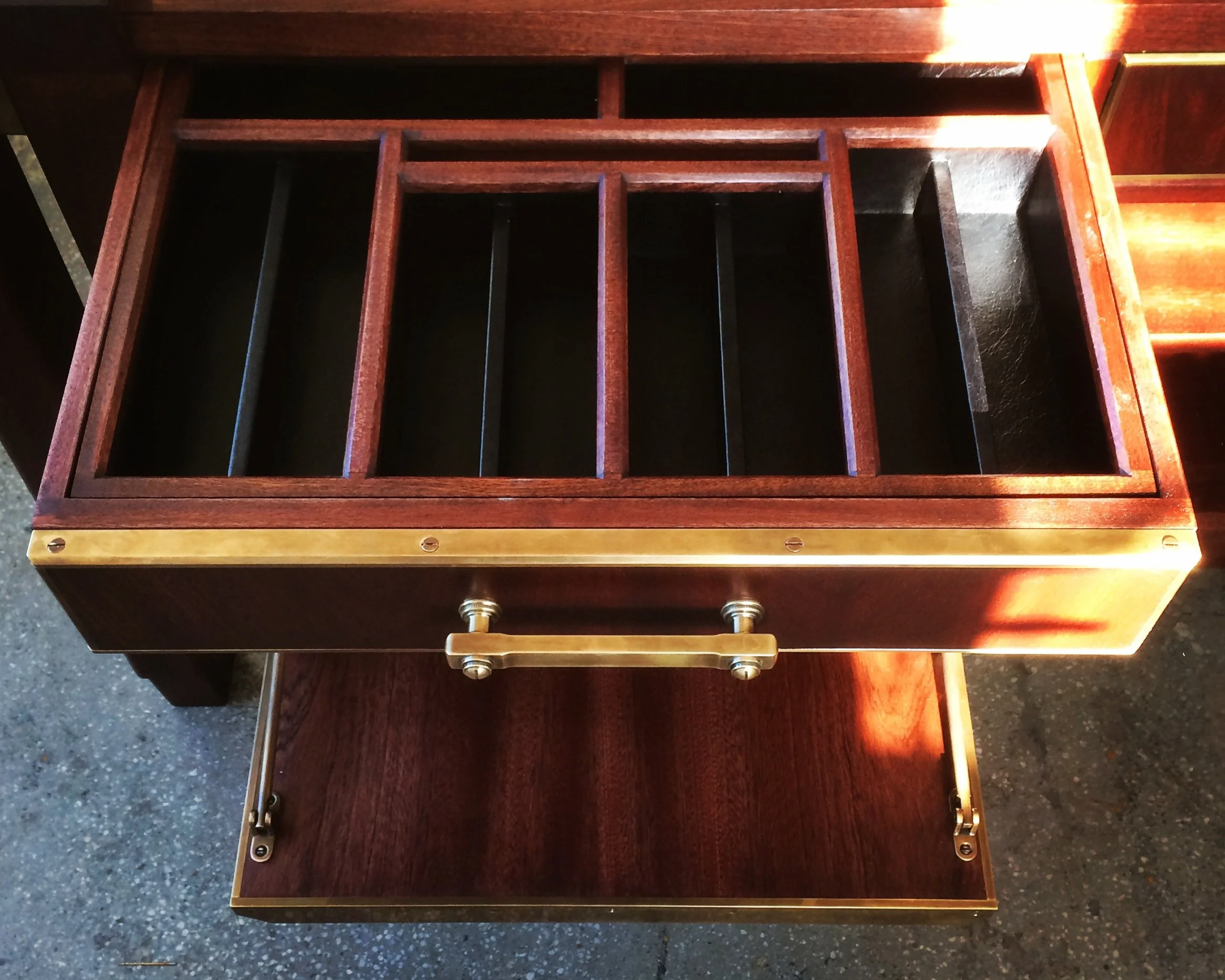 A black leather wrapped drawer interior with multiple compartments.  Bespoke brass accents and hardware with dark wooden hand-cut dovetail construction. Custom furniture. Made in New York City.  Brooklyn.  Wallpaper Magazine.