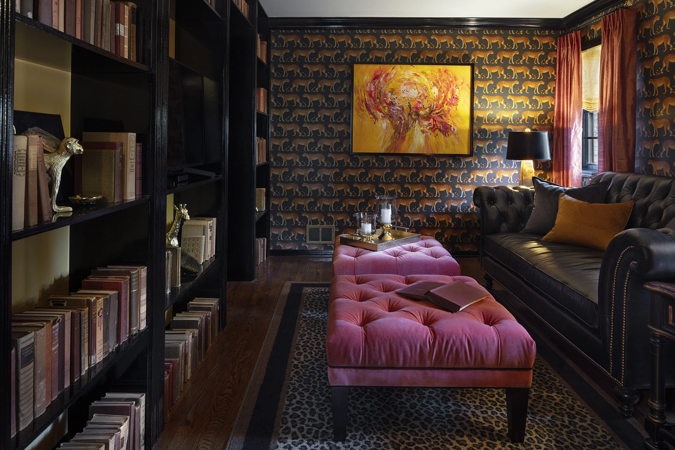Dramatic black library den with leather sofa and orange pink accents by Adam Zollinger Interiors