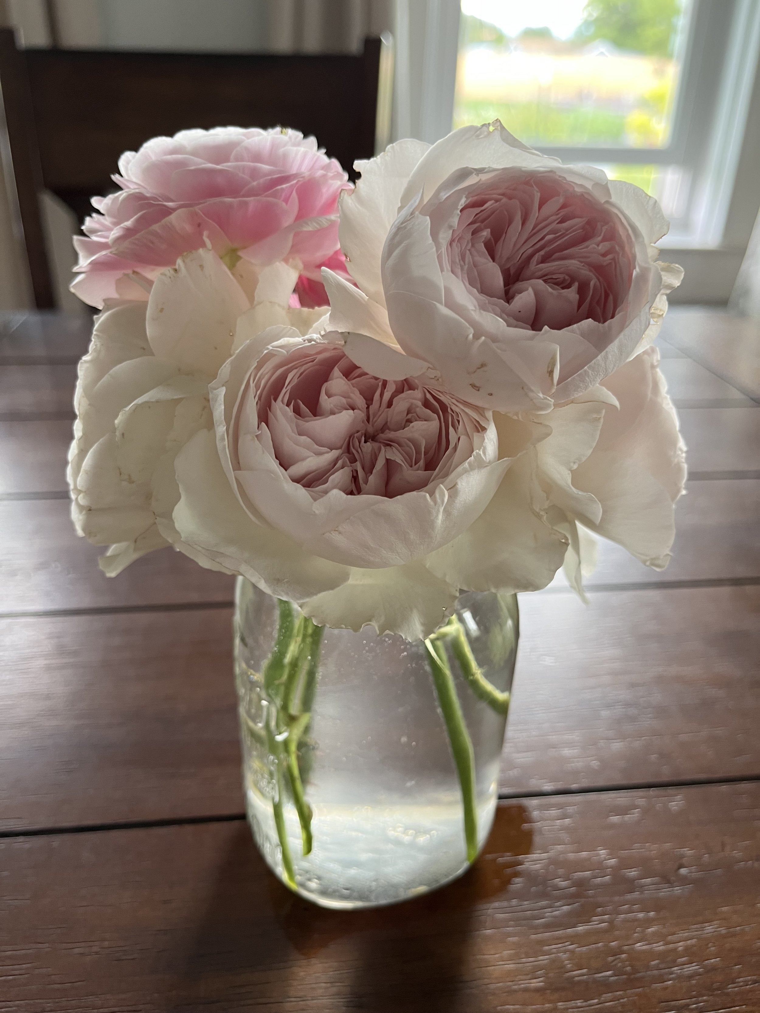 a jar of pink and white roses on a table