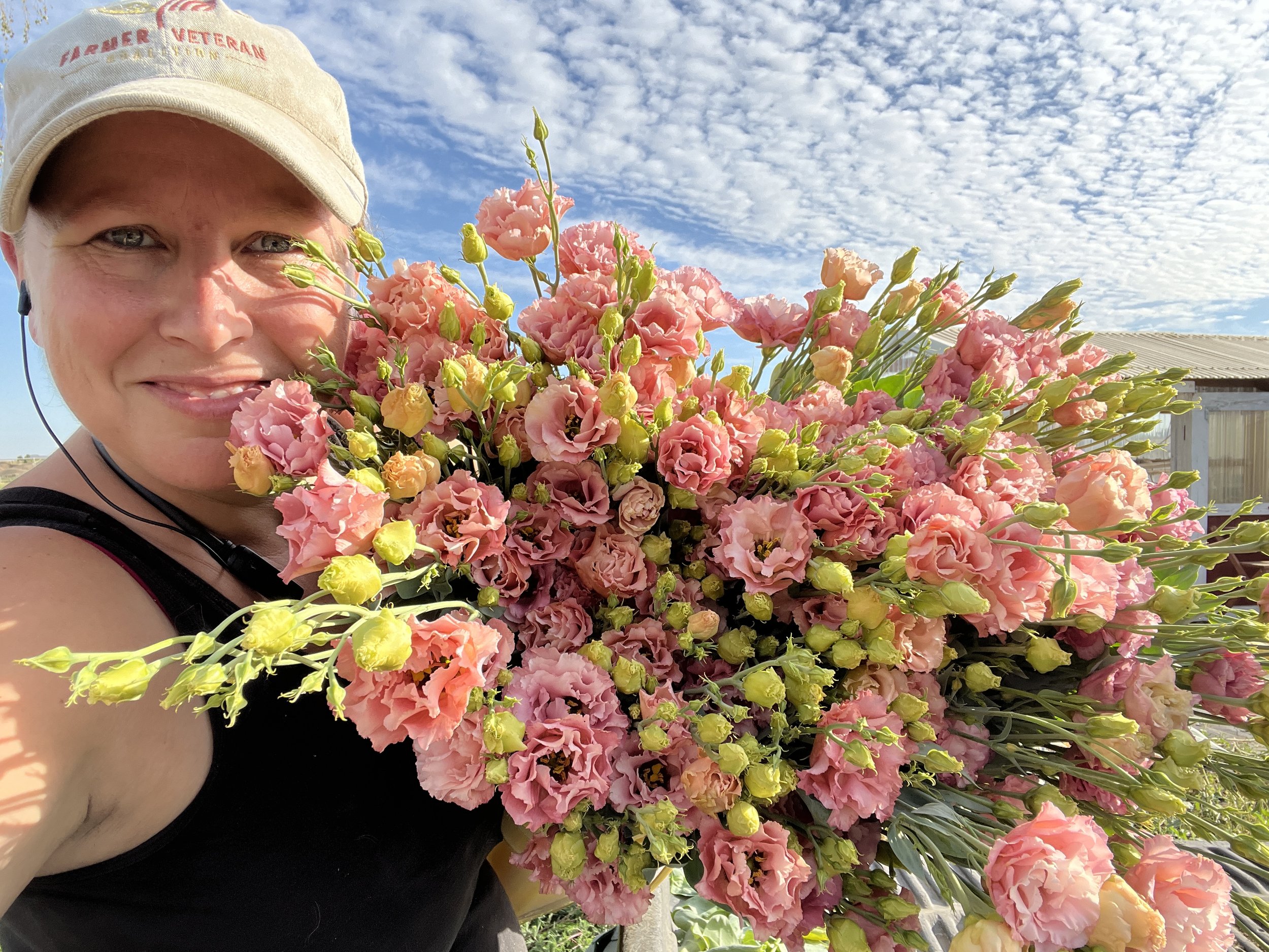a farmer taking a selfie with a bunch of pink flowers