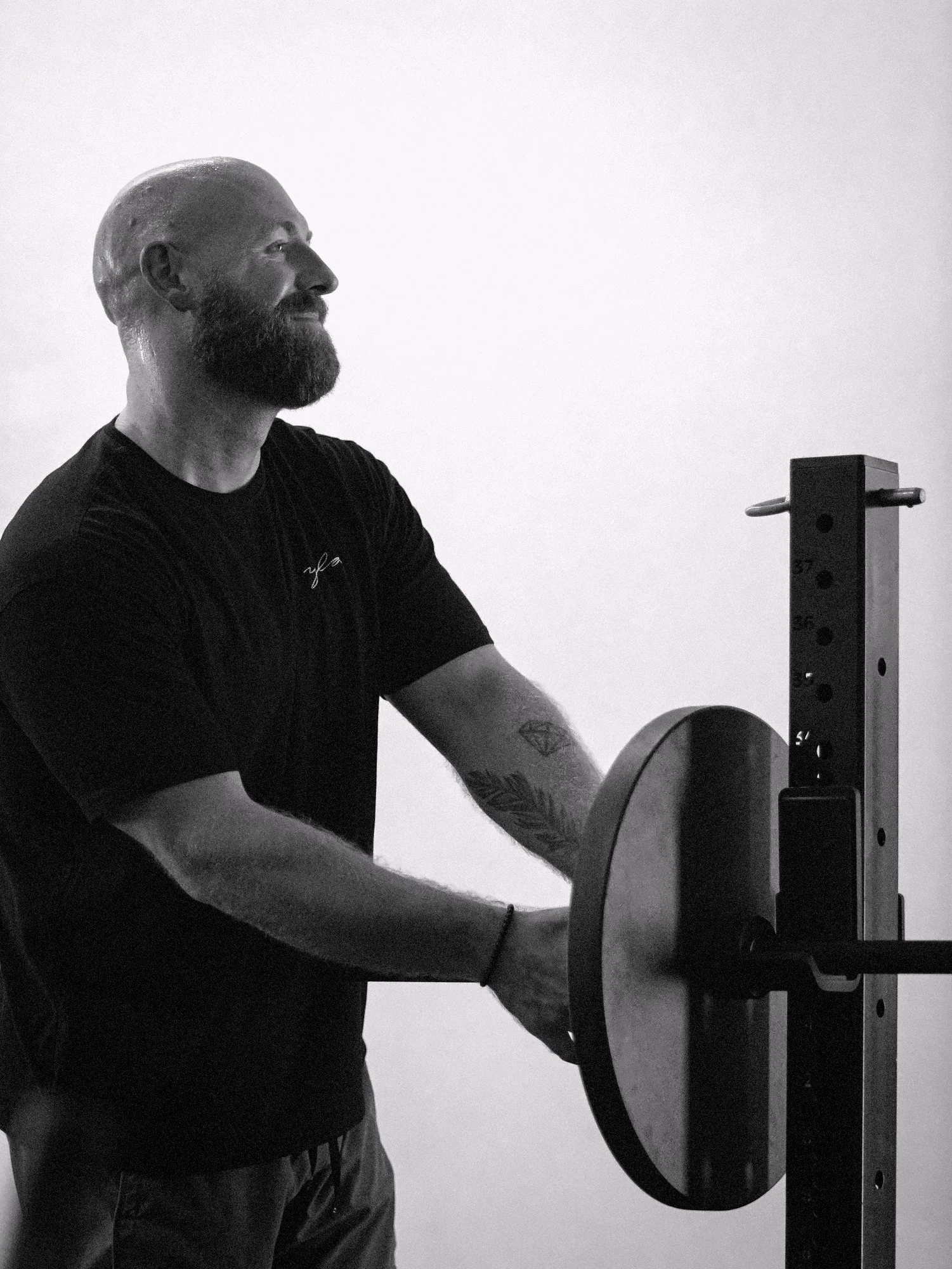 Coach Mike Wollard loading a weight plate onto a squat rack