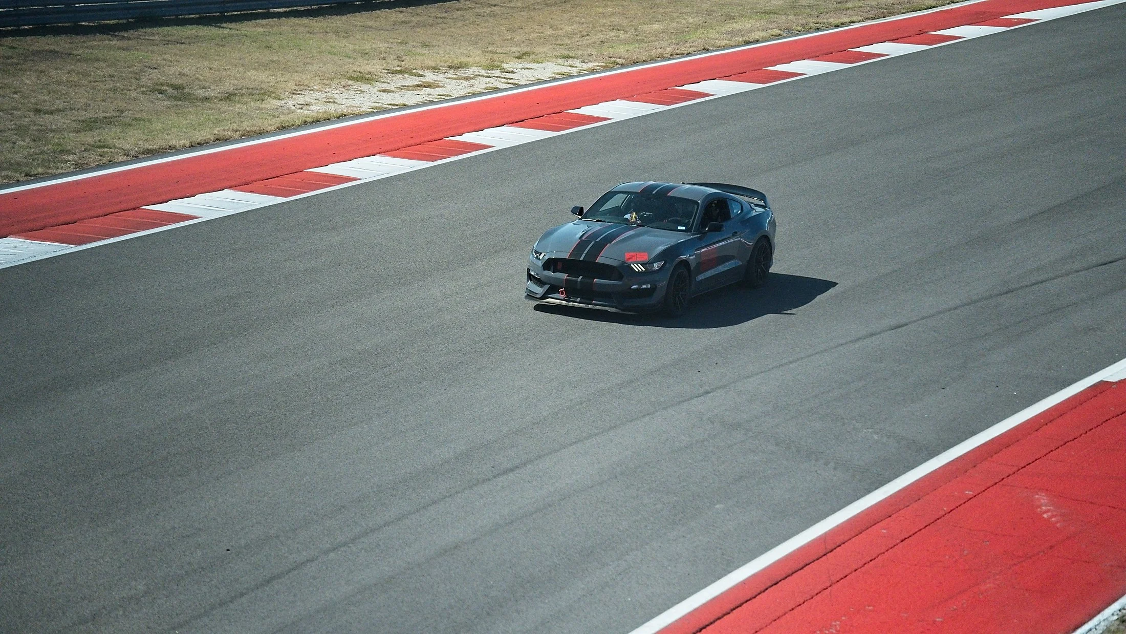 A black sports car with racing stripes on a race track.