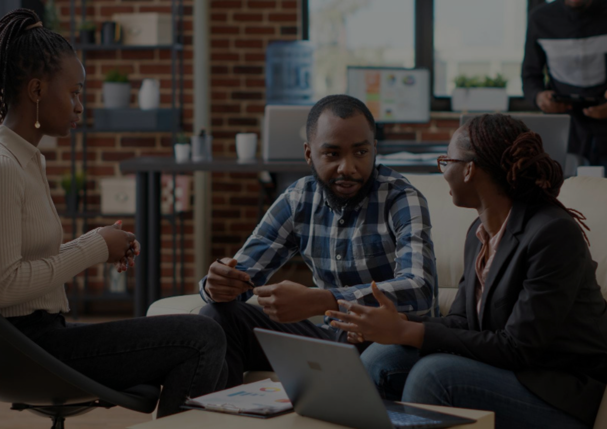 Three colleagues sitting together in a modern office in an ongoing workshop around a laptop.