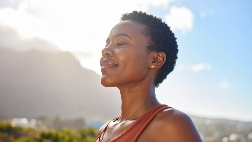 Changemaker practicing mindful breathing and grounding outdoors in a moment of reflection