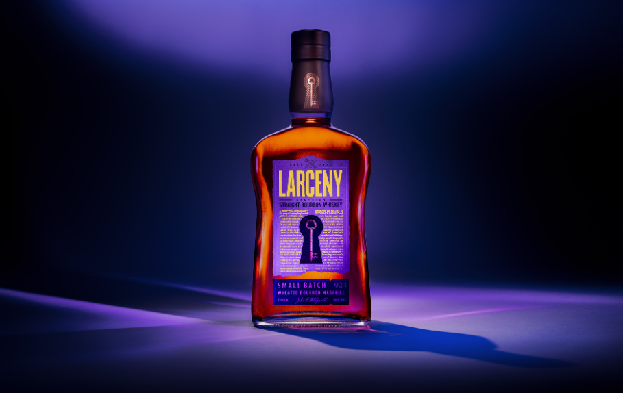 Bottle of Larceny small batch bourbon whiskey illuminated with purple and blue lighting, casting a shadow.