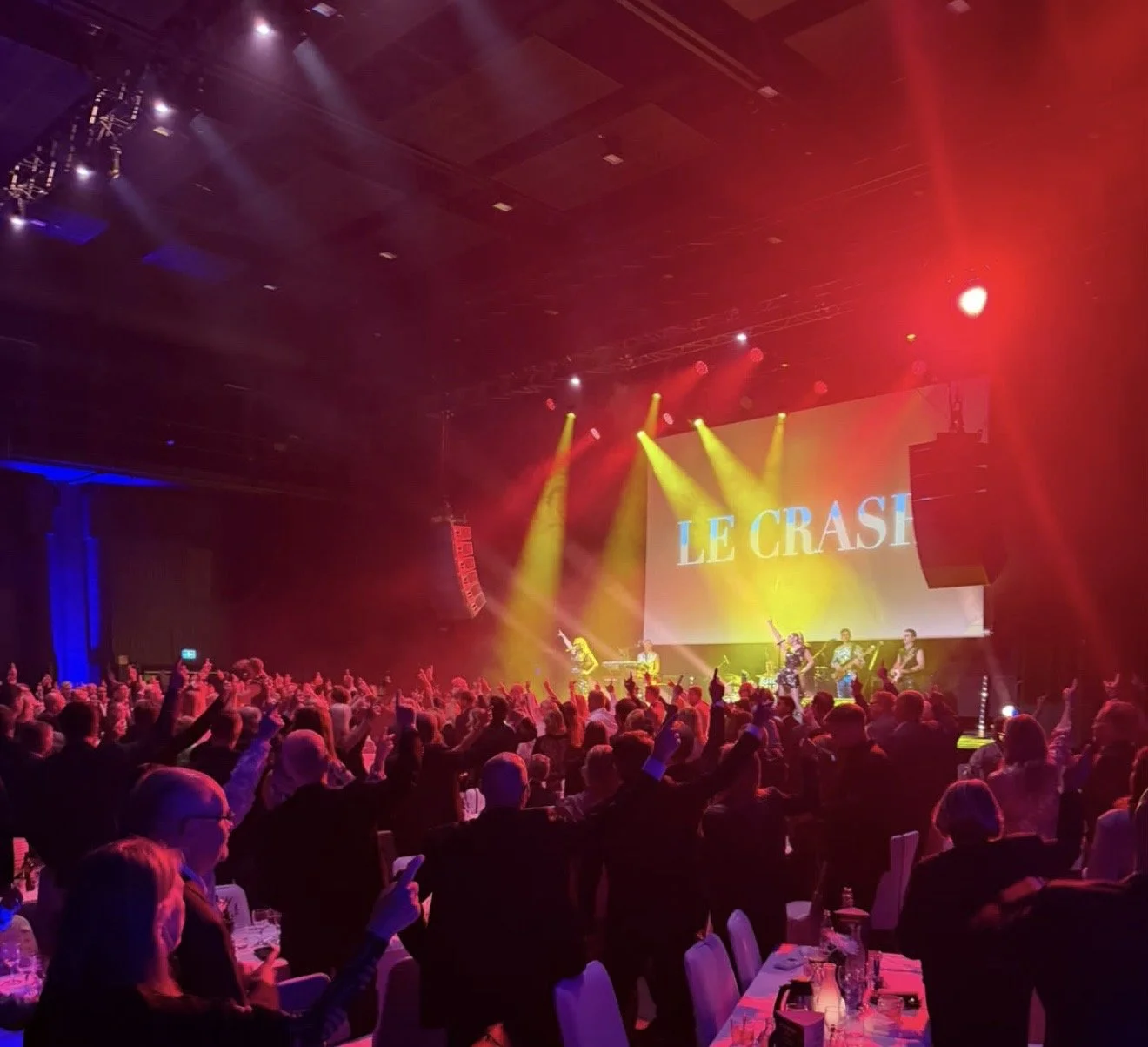Le Crash showar på en scen tillsammans med ett liveband och en publik som står upp och dansar