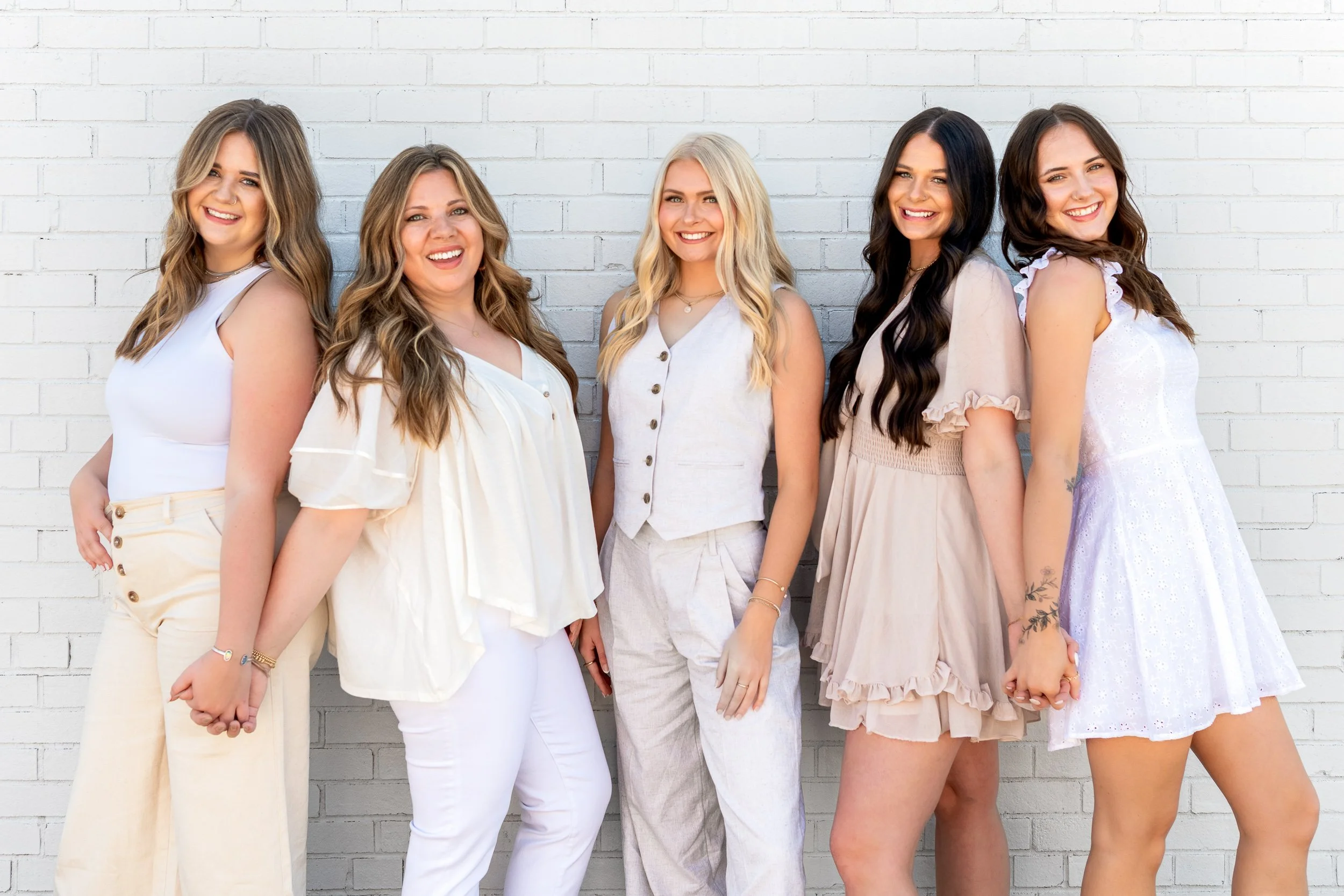 Hyde Salon team portrait against white brick wall in coordinated neutral styling