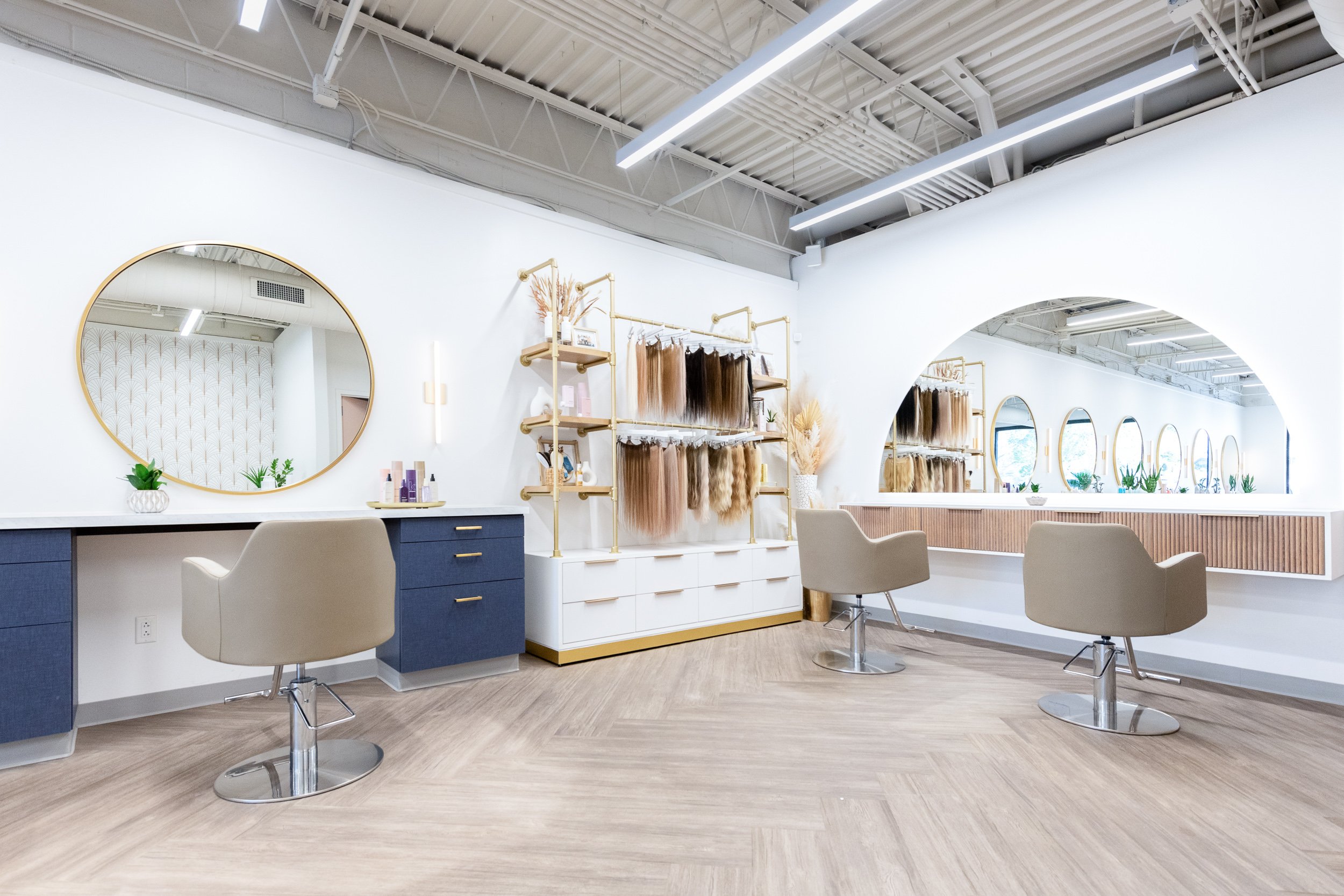 Wide interior view of Hyde Salon styling stations with gold mirrors and extension display