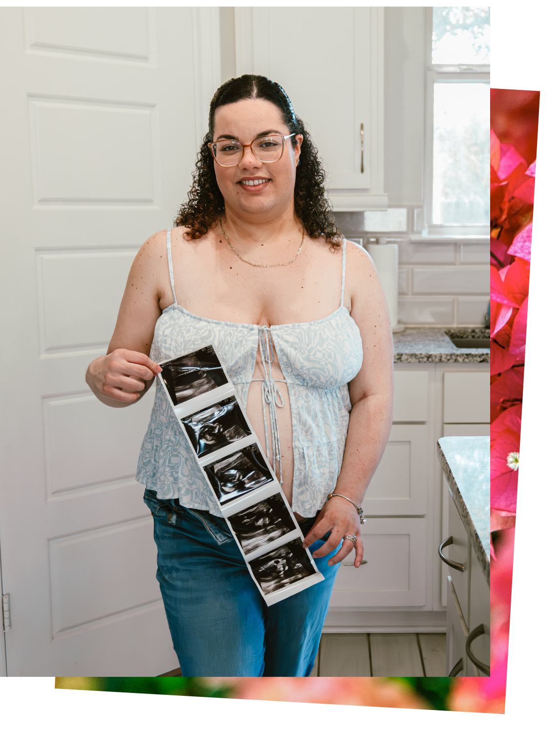 Woman with glasses holding a series of ultrasound pictures in a kitchen.