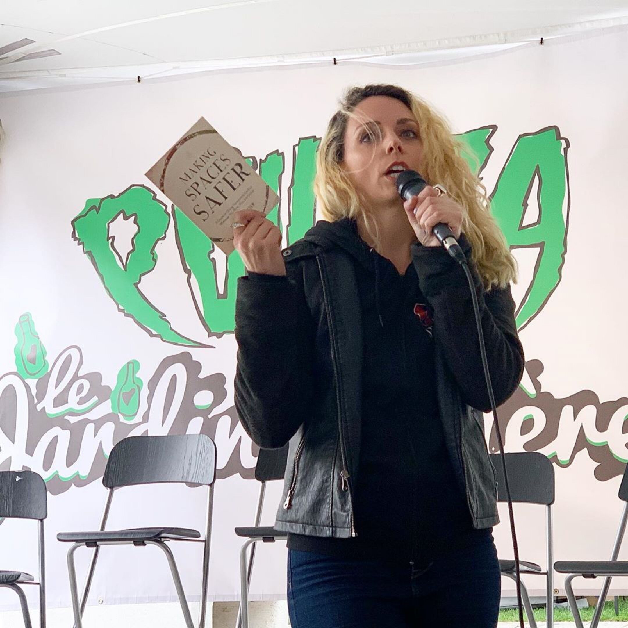 Shawna Potter holding up her book speaking into a microphone at Pouzza music festival in 2019..JPG