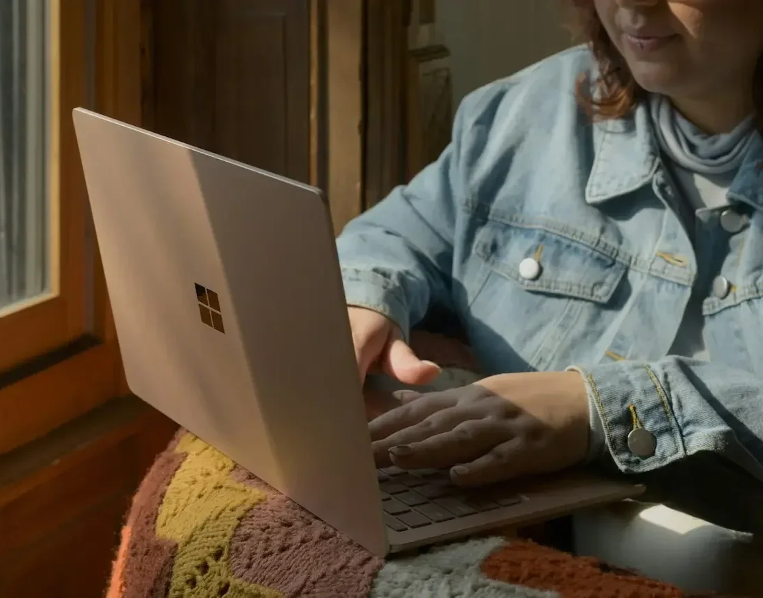 Fat nonbinary person with a shag haircut working on a laptop in sunlight. Answers to FAQs about body image trust and neurodivergent-affirming care.