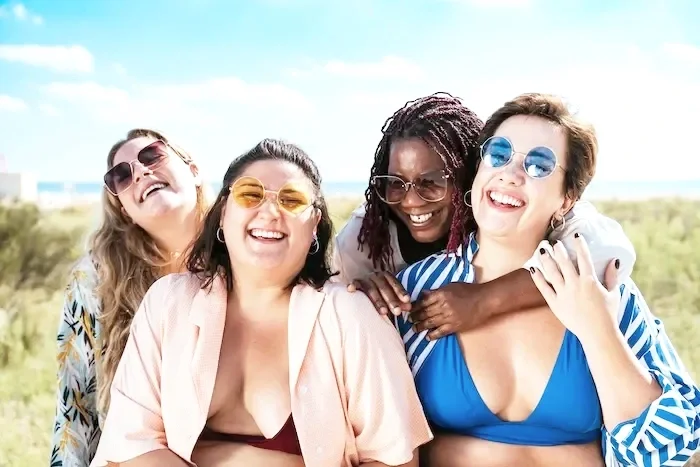 Friends in larger bodies smiling and standing close together.