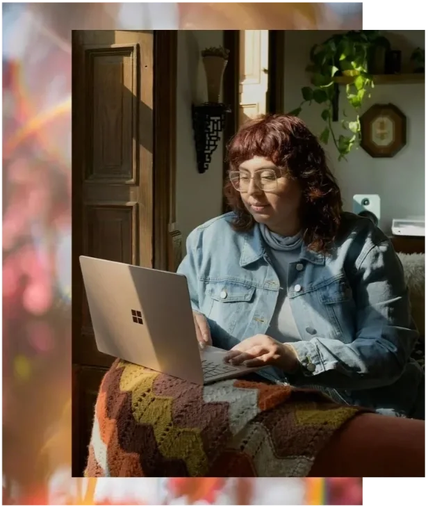 Fat nonbinary person with a shag haircut and denim jacket working on a laptop in sunlight. Neurodivergent-affirming body acceptance therapy in California.